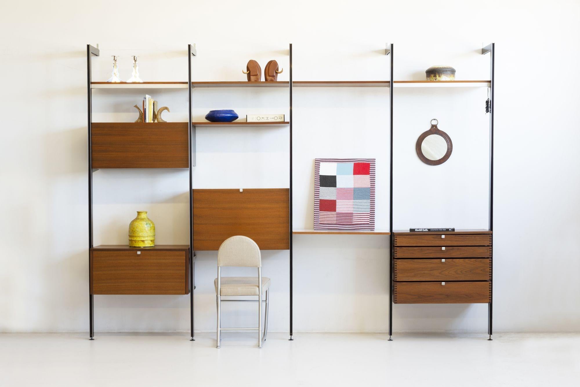 George Nelson & Associates CSS (Comprehensive Shelving System) for Herman Miller:
The system is comprised of five aluminum uprights with six shelves, 2 with light sources, 
A Dropdown desk concealing 2 drawers with white porcelain pulls and a