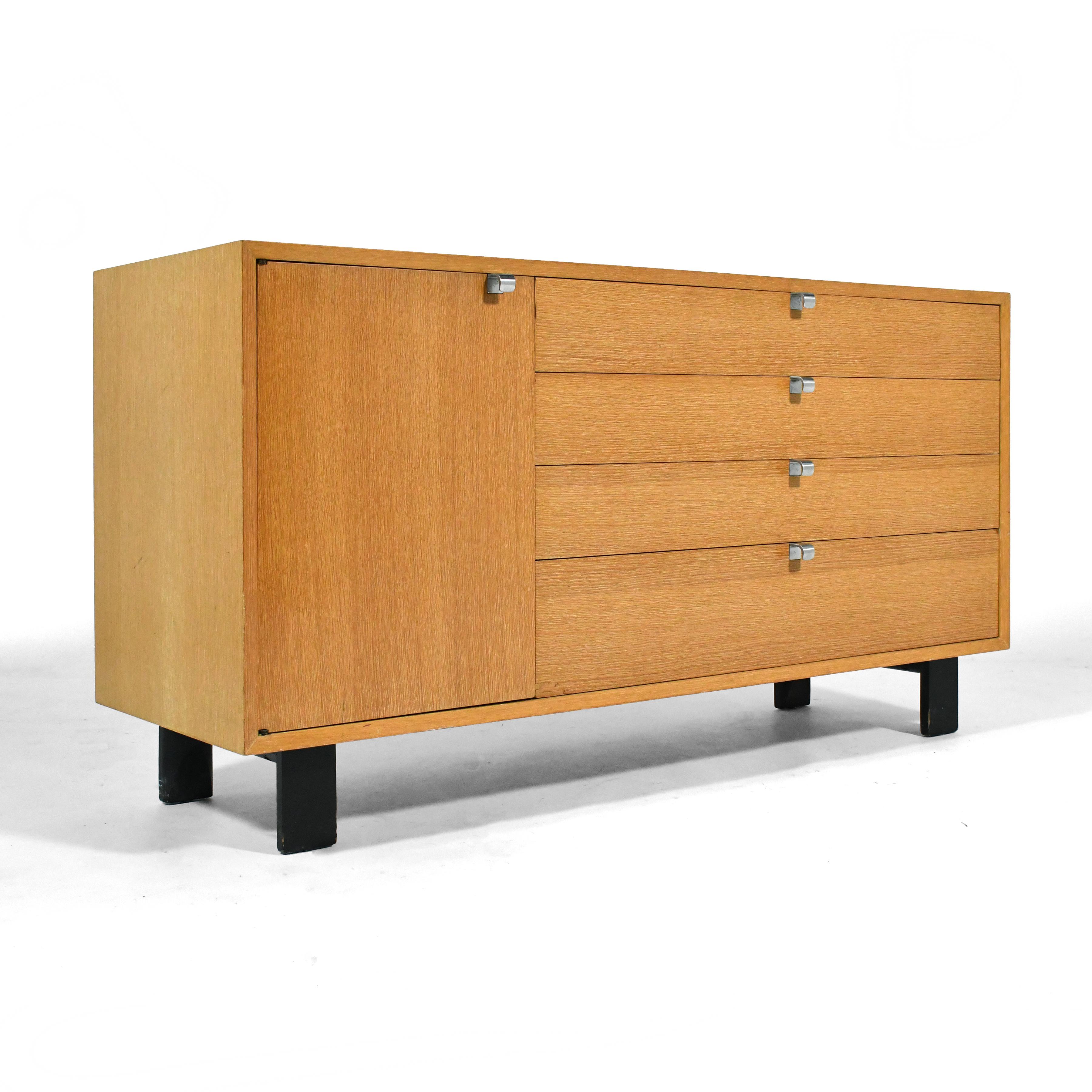 From Nelson versatile line of case goods for Herman Miller, this model 4712 basic cabinet group chest features four doors and a door concealing an adjustable shelf in an asymmetrical arrangement. The combed oak cabinet has brushed silver J shaped