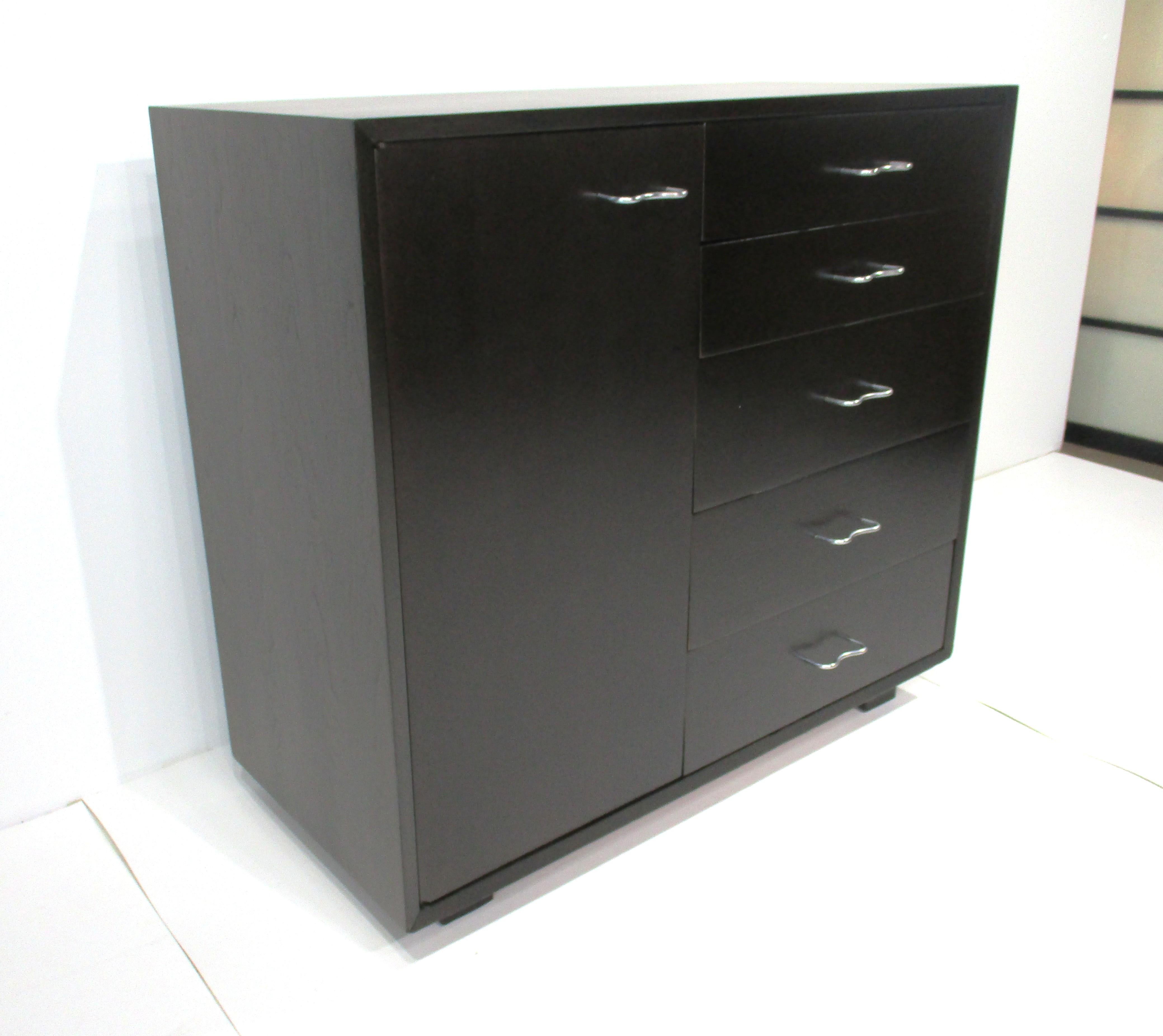 Très belle commode ou armoire reposant sur des pieds plus courts, en finition ébène foncé, avec une porte latérale comportant deux étagères réglables. L'autre côté dispose de cinq tiroirs , tous avec des poignées sculpturales en acier inoxydable et