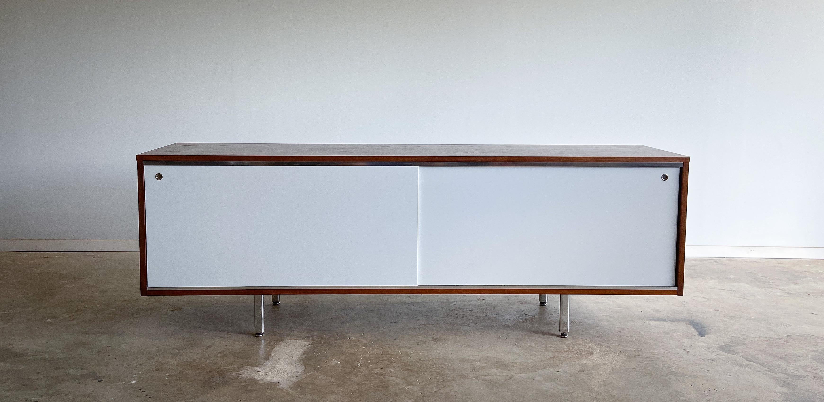 A wonderful credenza designed by George Nelson for Herman Miller. Part of the Executive Office Group (EOG) line designed for executive offices of the period. 

Featuring lovely walnut top and sides, beautifully accented by white lacquered sliding