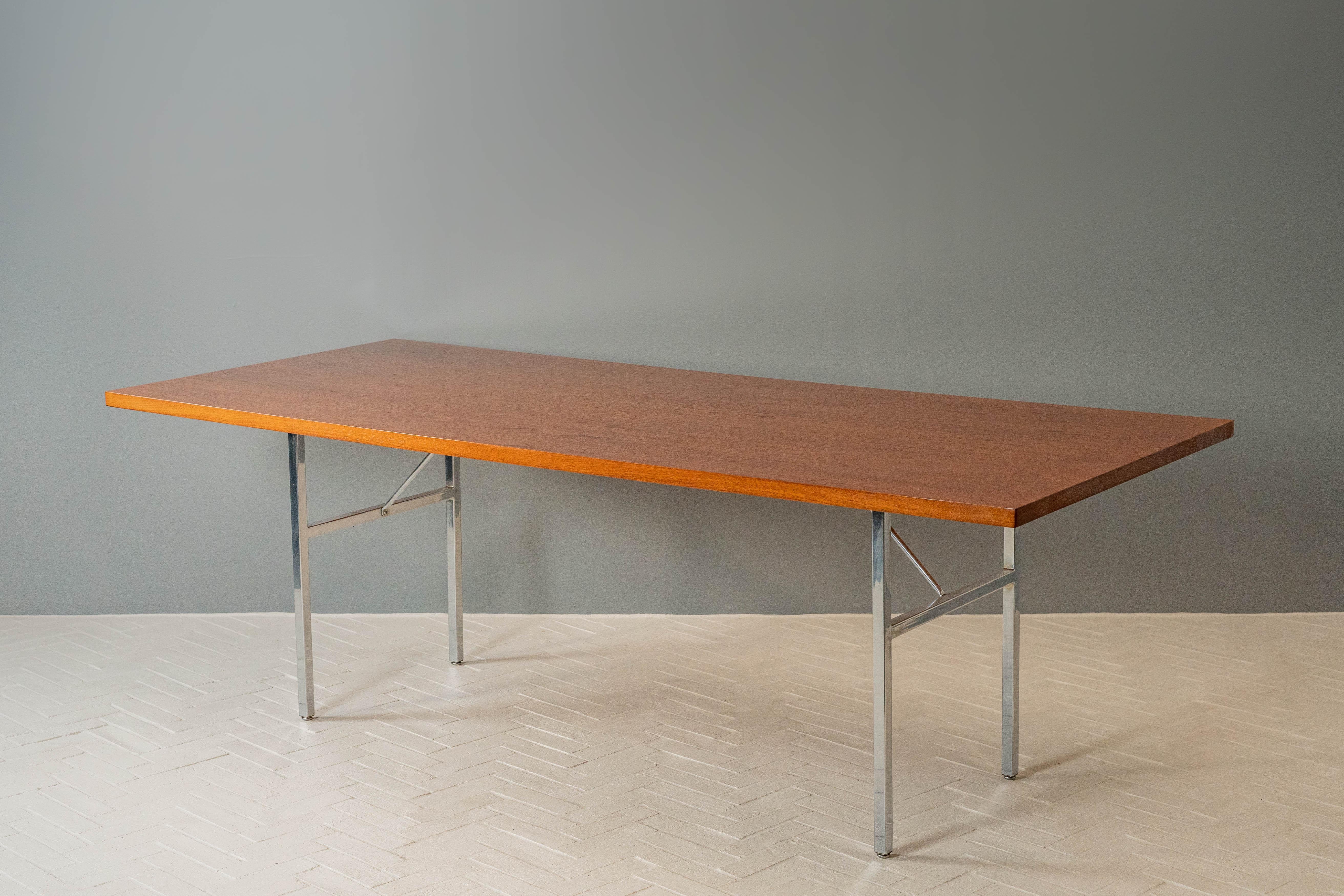 USA, ca. 1950s. A large dining table or work table from George Nelson’s Executive Office Group for Herman Miller. Features a generous rectangular walnut top supported by sturdy architectural chromed steel H-shape legs with angled tubular supports.