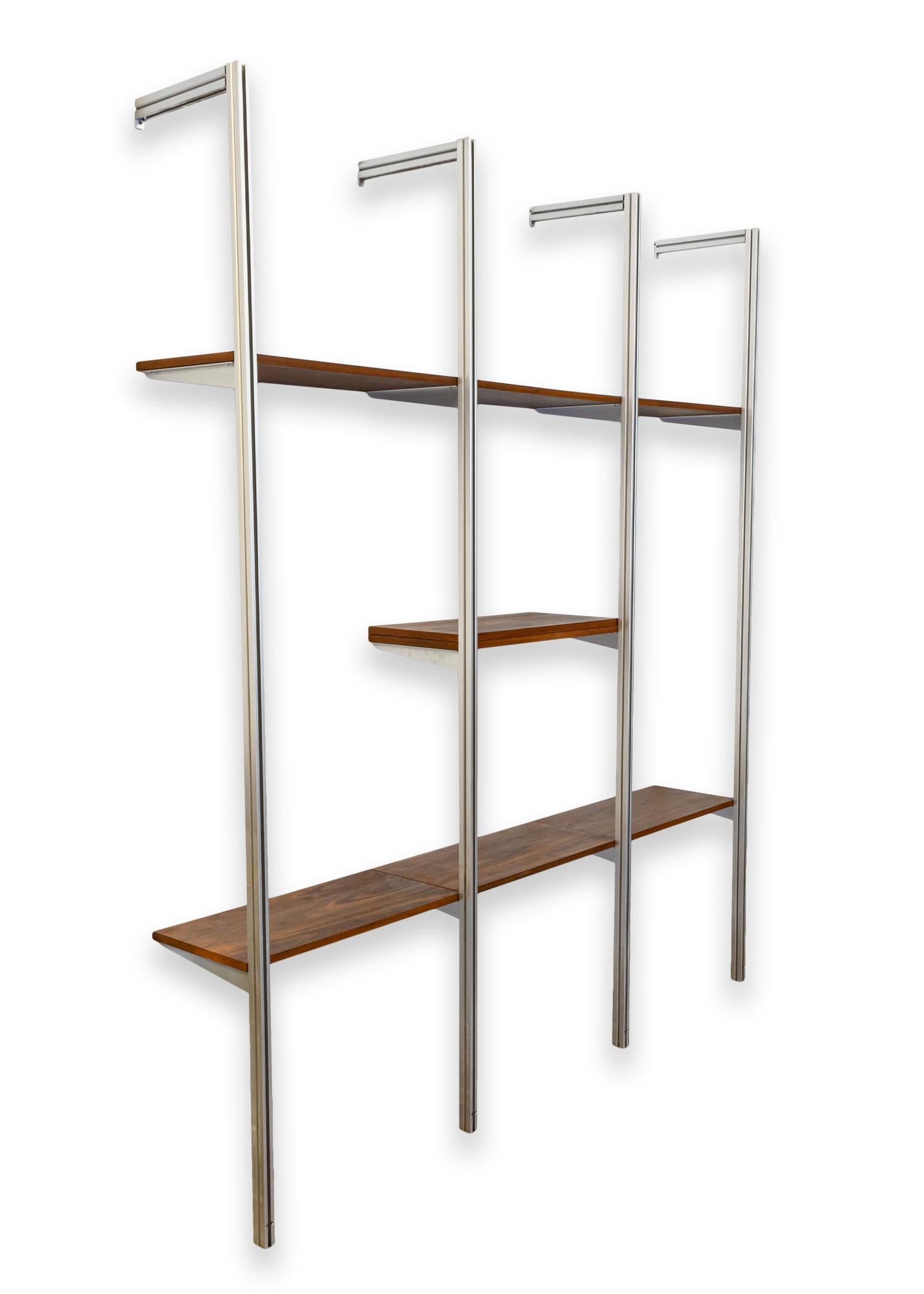 An Omni system wall unit by George Nelson for Herman Miller. A gorgeous mid century modern wall unit featuring sleek, brushed aluminum framing, and walnut shelving. This piece has been recently refinished. This piece has 3 bays, and 7 shelves with