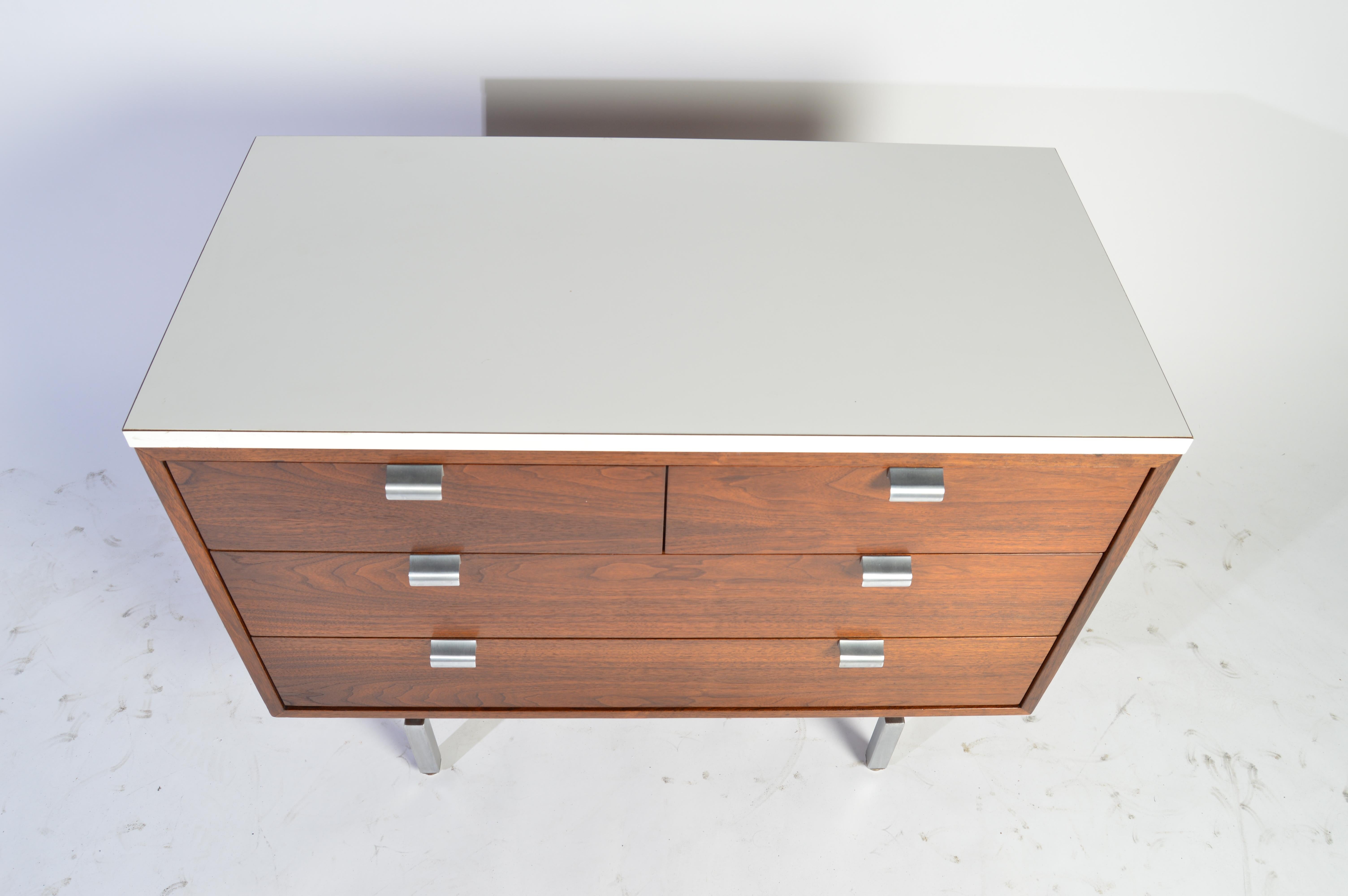 A sleek midcentury cabinet designed by George Nelson for Herman Miller in walnut having 4 drawers, aluminum pulls over an aluminum frame with white laminate top.
Beautiful condition inside and out.