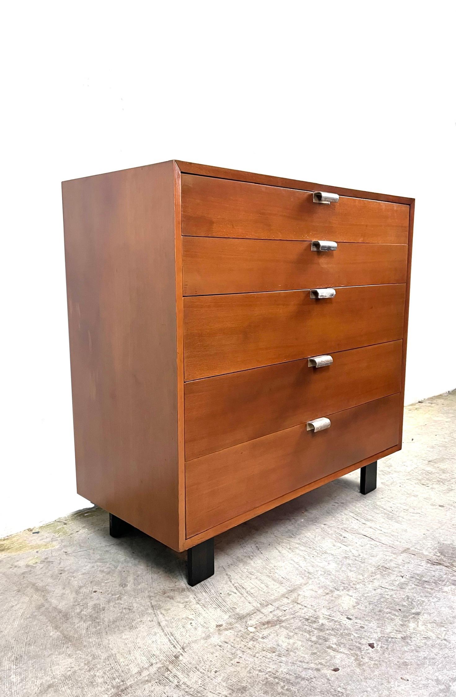Highboy dresser by George Nelson for Herman Miller, c.1950’s. This five-drawer dresser features a walnut frame with sculpted original chrome plated metal pulls. Top drawer features separations for smaller belongings. Rests on Ebonized wooden black