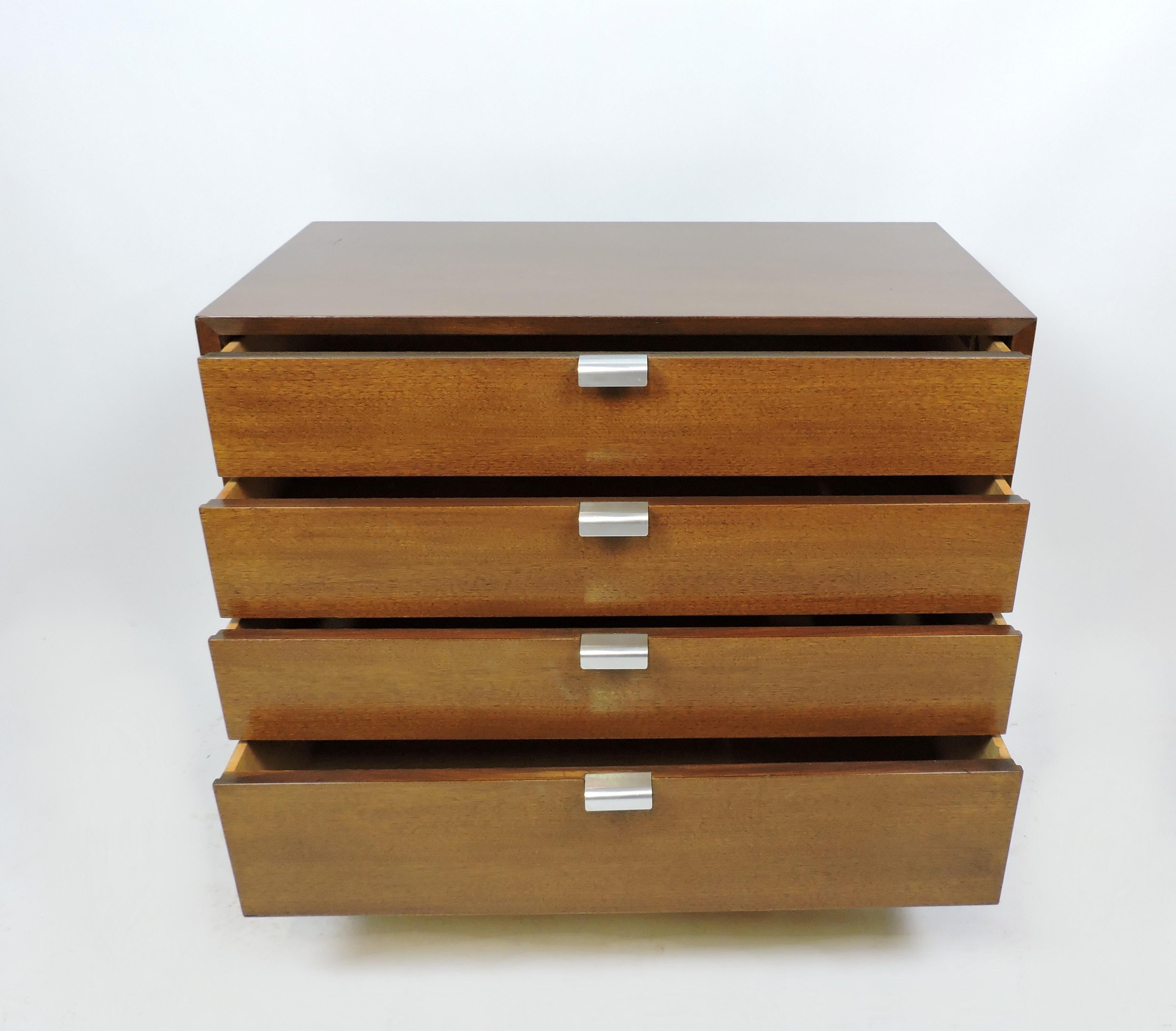 Handsome and distinctive walnut chest of drawers designed by George Nelson and manufactured by Herman Miller. Part of the Basic Cabinet Series, this cabinet has four drawers. Classic J shaped aluminum pulls and black block feet complete the look.