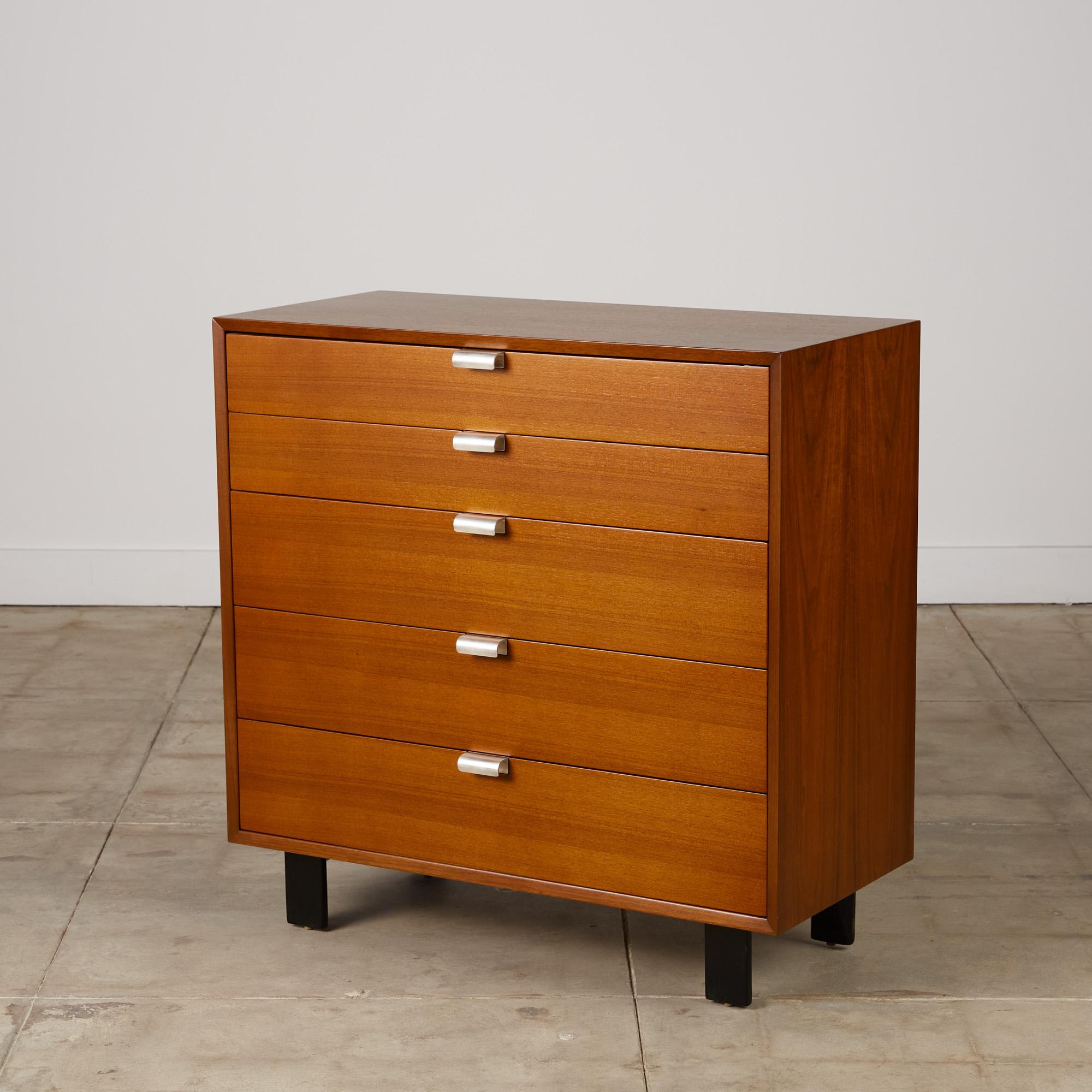 Dresser by George Nelson for Herman Miller, c.1950s. This five-drawer dresser features a walnut frame with sculpted aluminum pulls and sits atop a black plinth with four short black legs. The top drawer features separations for smaller belongings