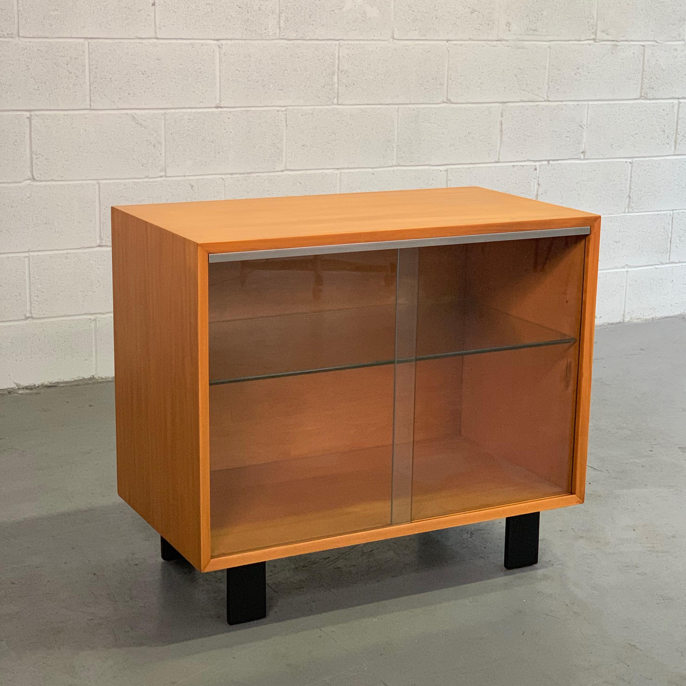 Mid-Century Modern, natural birch cabinet by George Nelson for Herman Miller features sliding glass door fronts with contrasting black lacquered legs. There is one interior glass shelf. The cabinet itself is 24 inches ht.