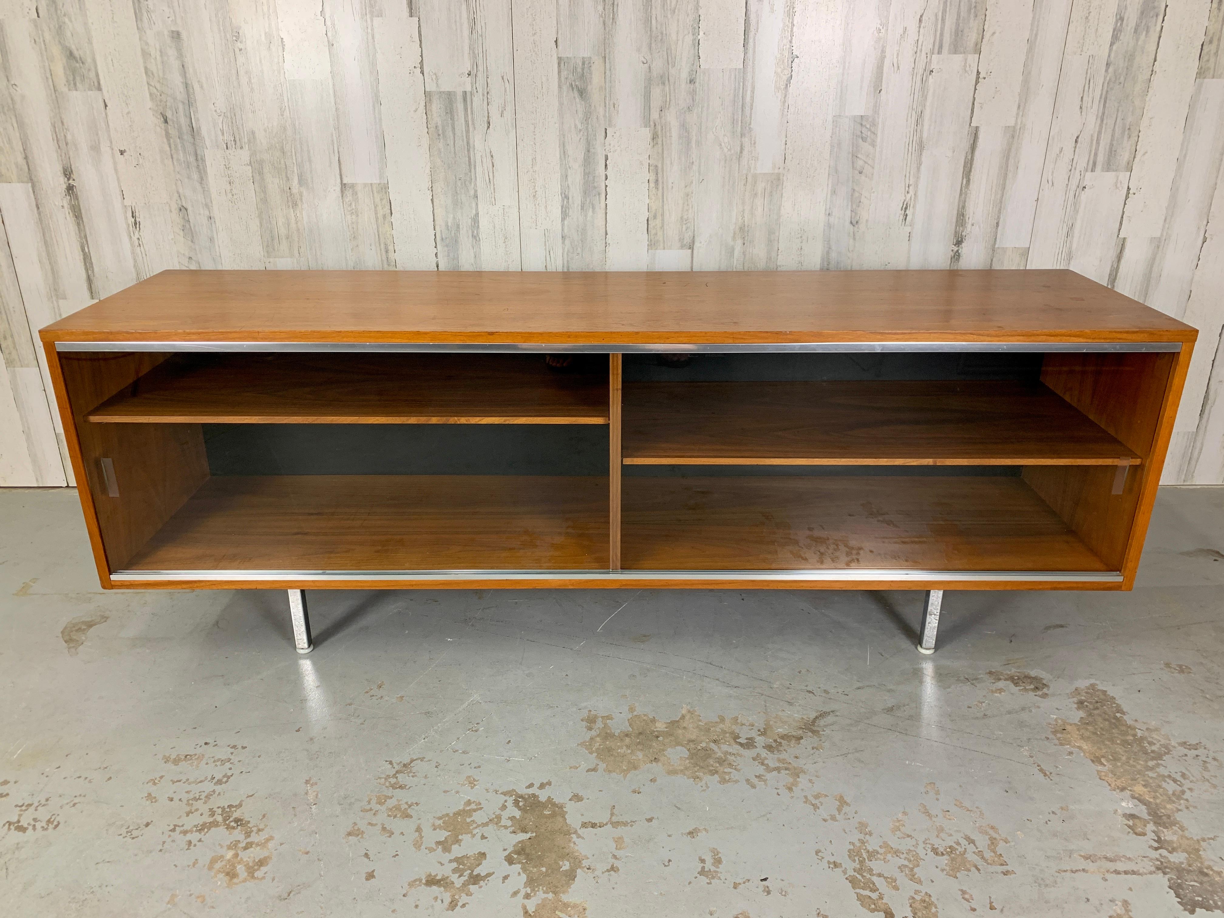 Rare Glass sliding doors on a walnut display cabinet with adjustable shelves.
Chrome legs with original Domes of silence glides.
The Herman Miller badge is missing, please see pictures of where the badge was located.
All original condition.