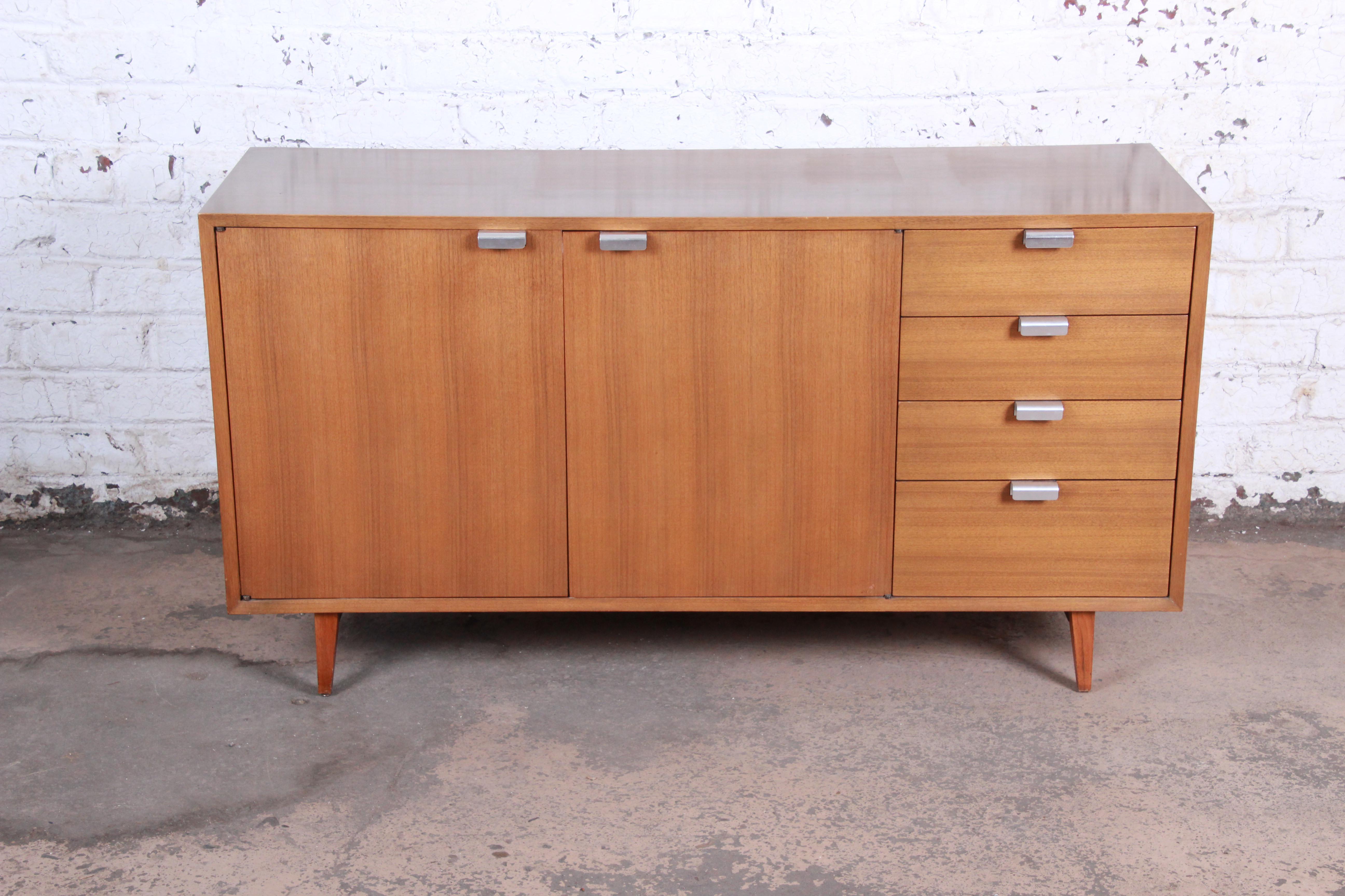 An exceptional Mid-Century Modern sideboard or credenza by George Nelson for Herman Miller. The credenza features gorgeous primavera wood grain and Minimalist midcentury design. It offers good storage, with a shelved cabinet behind two doors on the