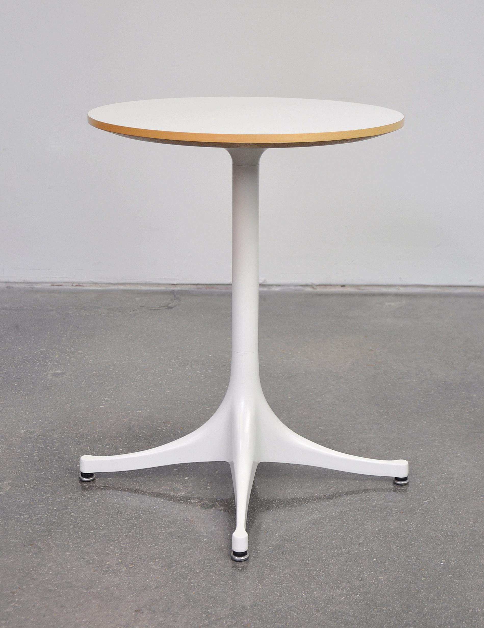 Classic Mid-Century Modern round end table with white powder-coated aluminium base with self-levelling glides and a white top with maple edge. First designed by George Nelson for Herman Miller in 1954, of simple and elegant form, this table can be