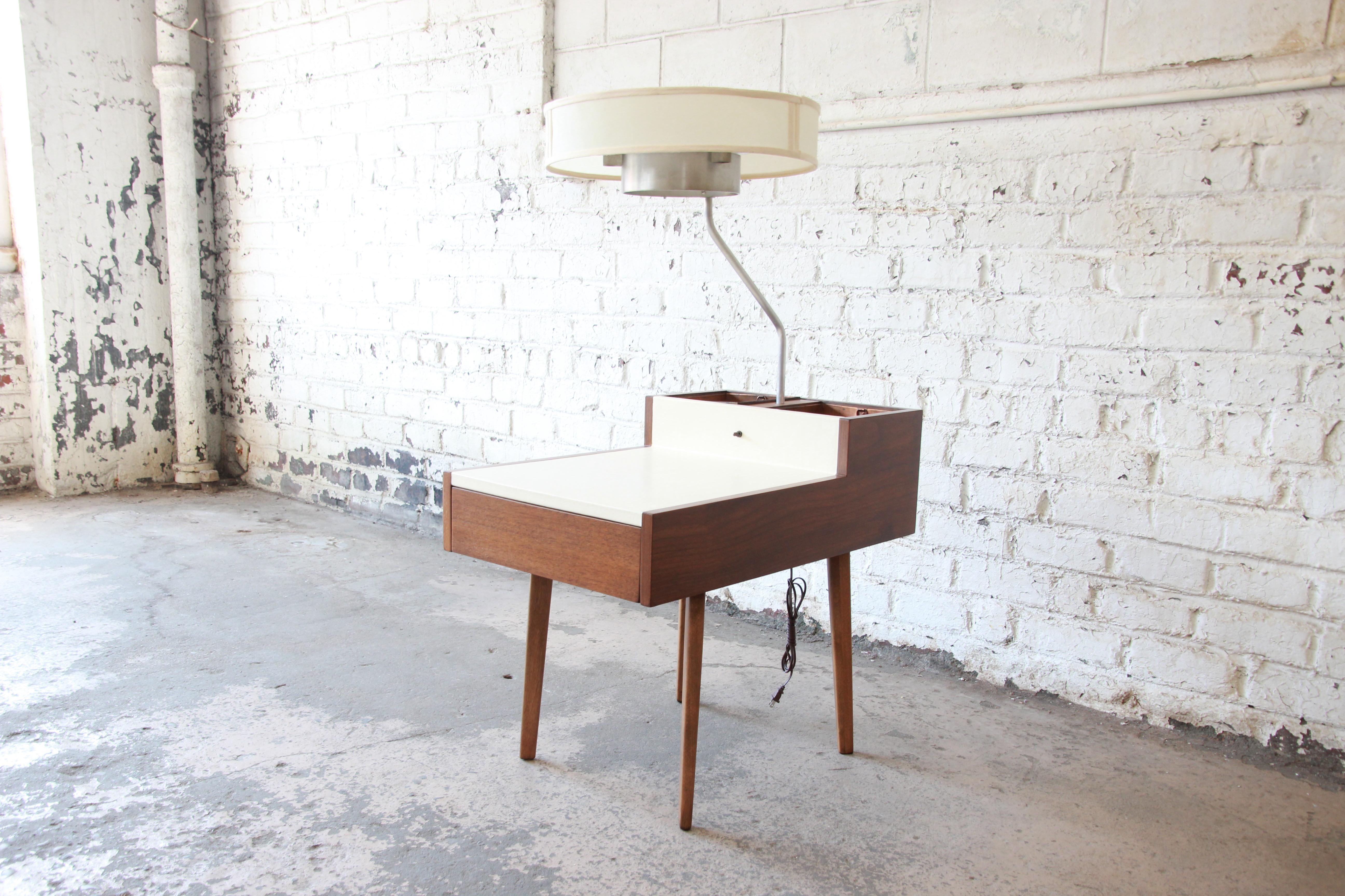 A rare and exceptional Mid-Century Modern lamp table designed by George Nelson for Herman Miller. The table features a white leather tabletop and a gorgeous walnut case that rests on four tapered and splayed walnut legs. There is a single divided