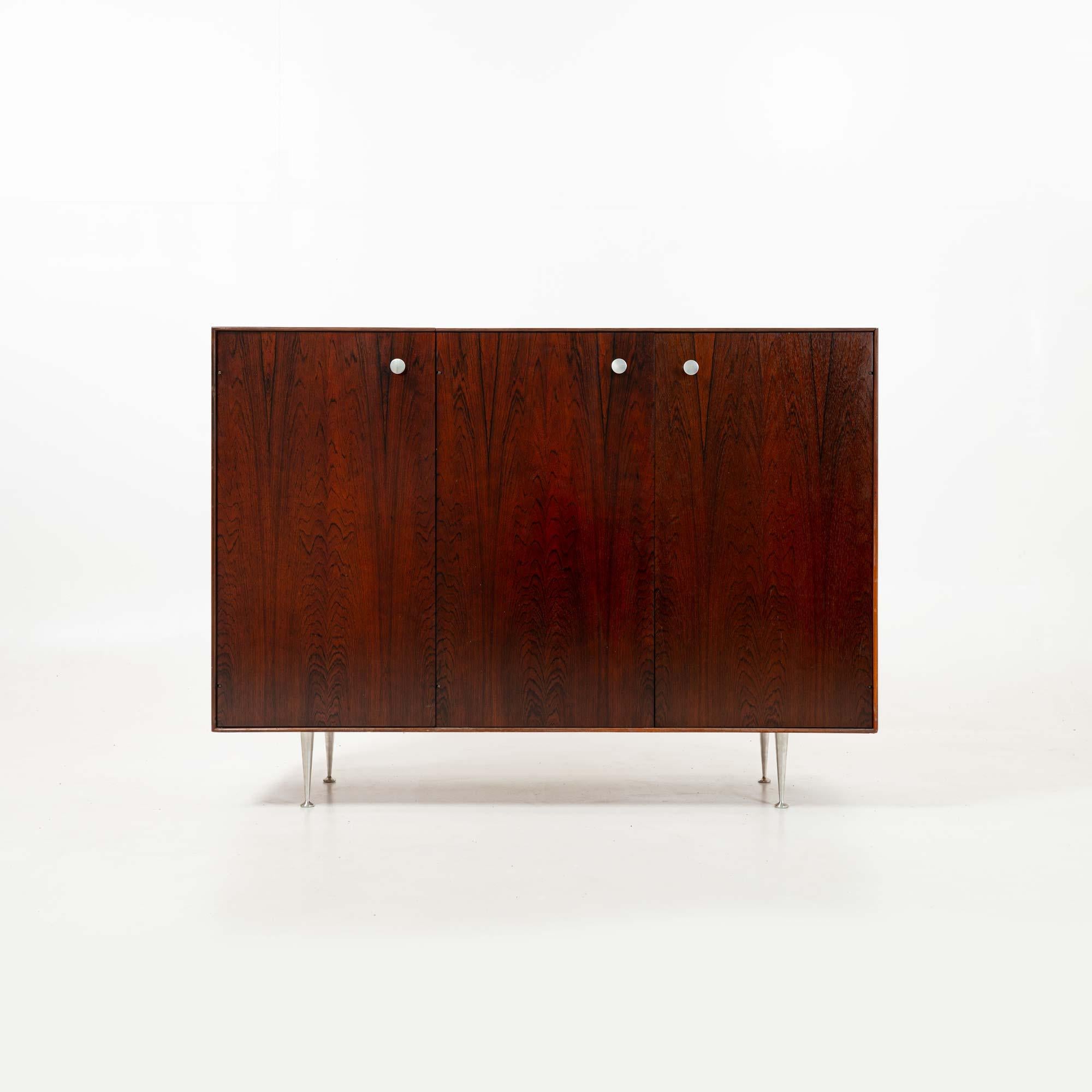 Raro y único mueble bar George Nelson de palisandro, con espejo de caja de luz incorporado y enchufe eléctrico, hacia la década de 1970. El mueble puede utilizarse como tocador, con cinco  cajones y estanterías. El armario está en buen estado, listo