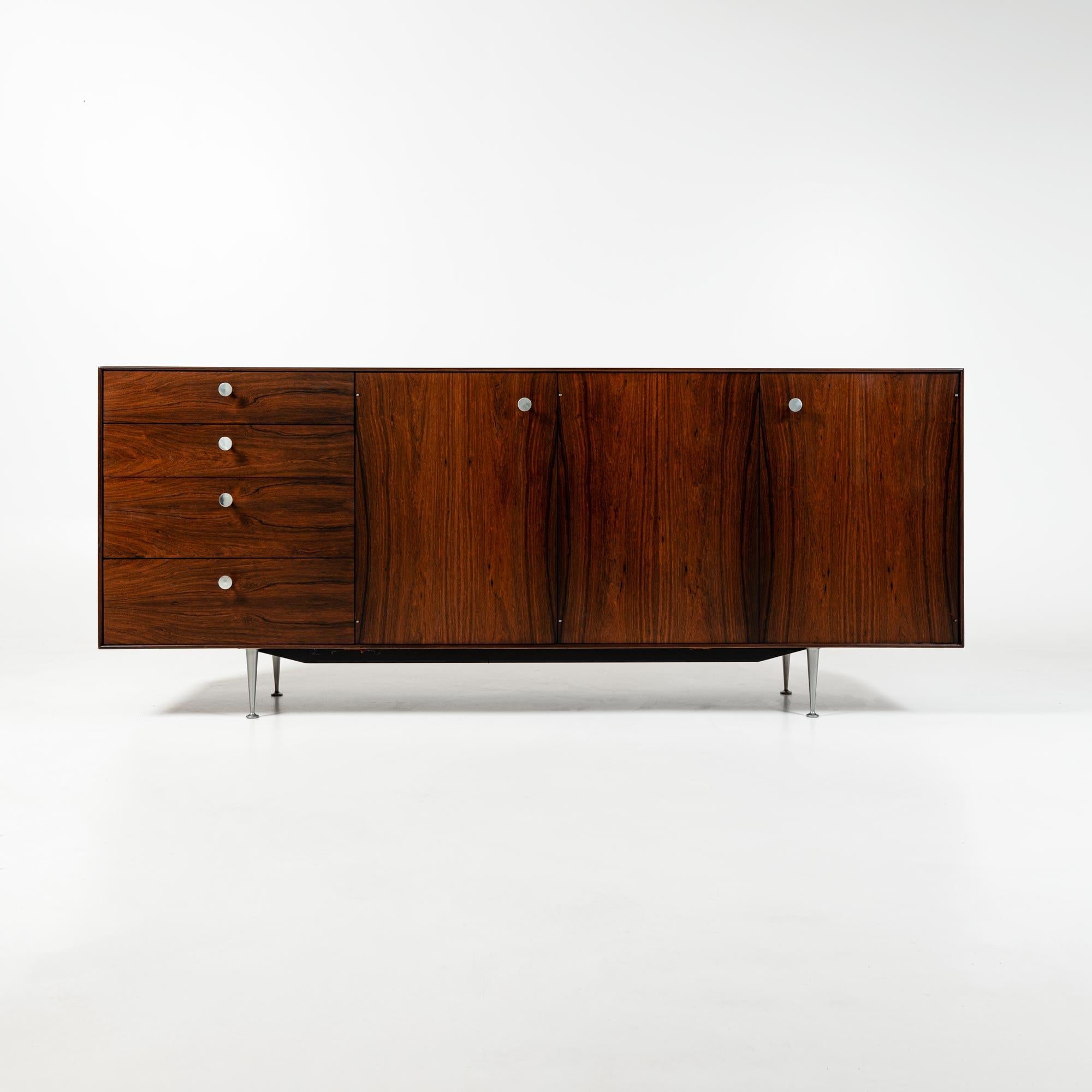 This is a rare Thin Edge credenza/cabinet in Rosewood from 1950s. It has several custom features including a cork-lined pull out for glassware, slits for cookie sheet storage, a pull out butcher's block cutting board, double utensil drawers and