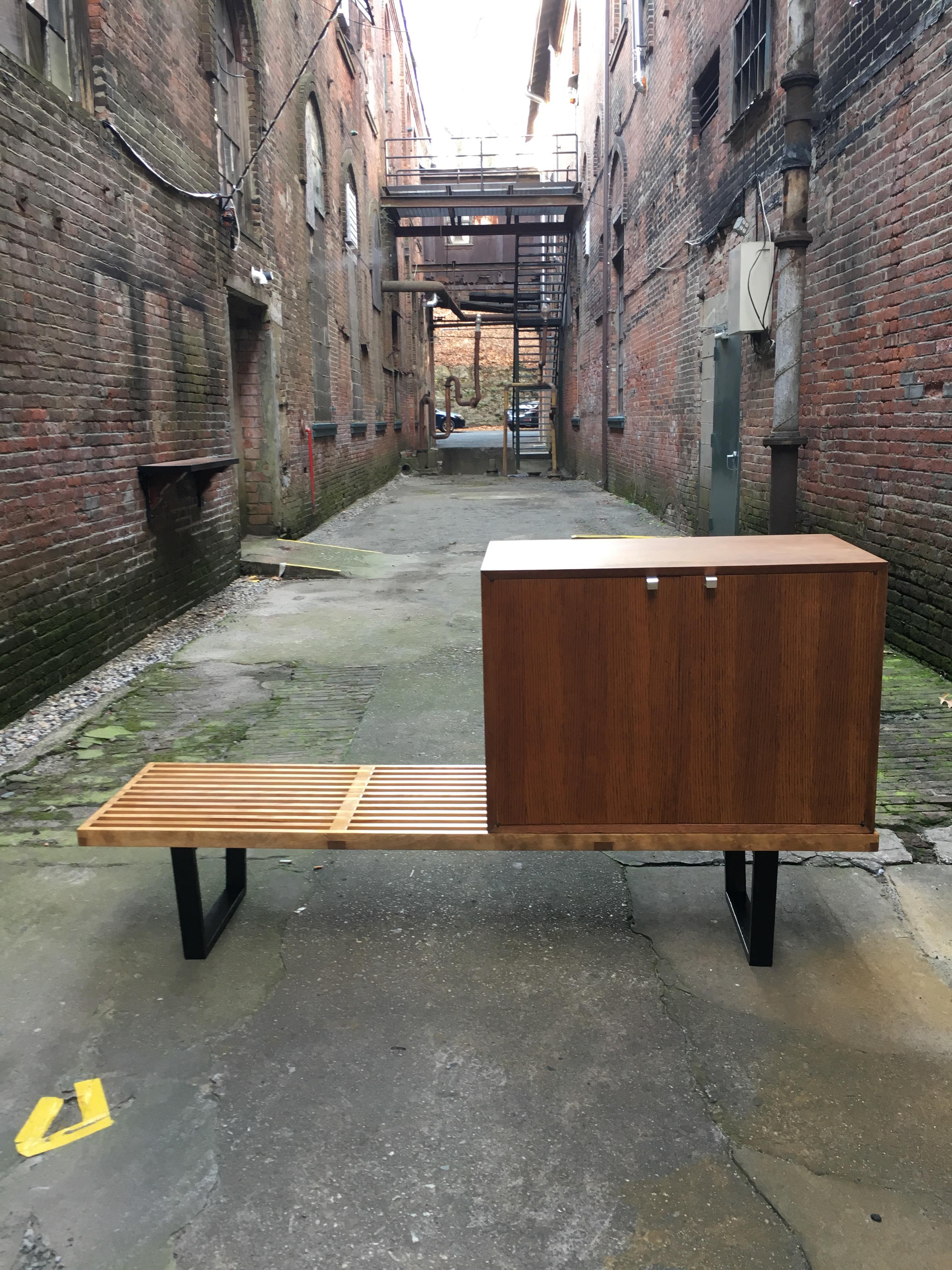 Early George Nelson for Herman Miller six foot slat bench and oak cabinet. The cabinet features signature chrome 'J' pull hardware and one adjustable shelf. Partial foil Herman Miller/George Nelson label on the underside of the bench. The beauty of
