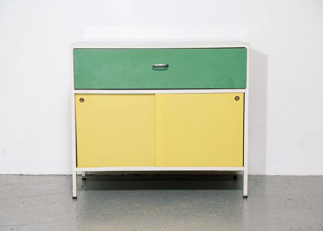 George Nelson Steelframe Case Series Cabinet. Configured with black linoleum top, green drawer, yellow sliding doors and grey sides. White steel frame.

Signed by the manufacturer inside drawer.

Produced by Herman Miller from 1954 to 1966.