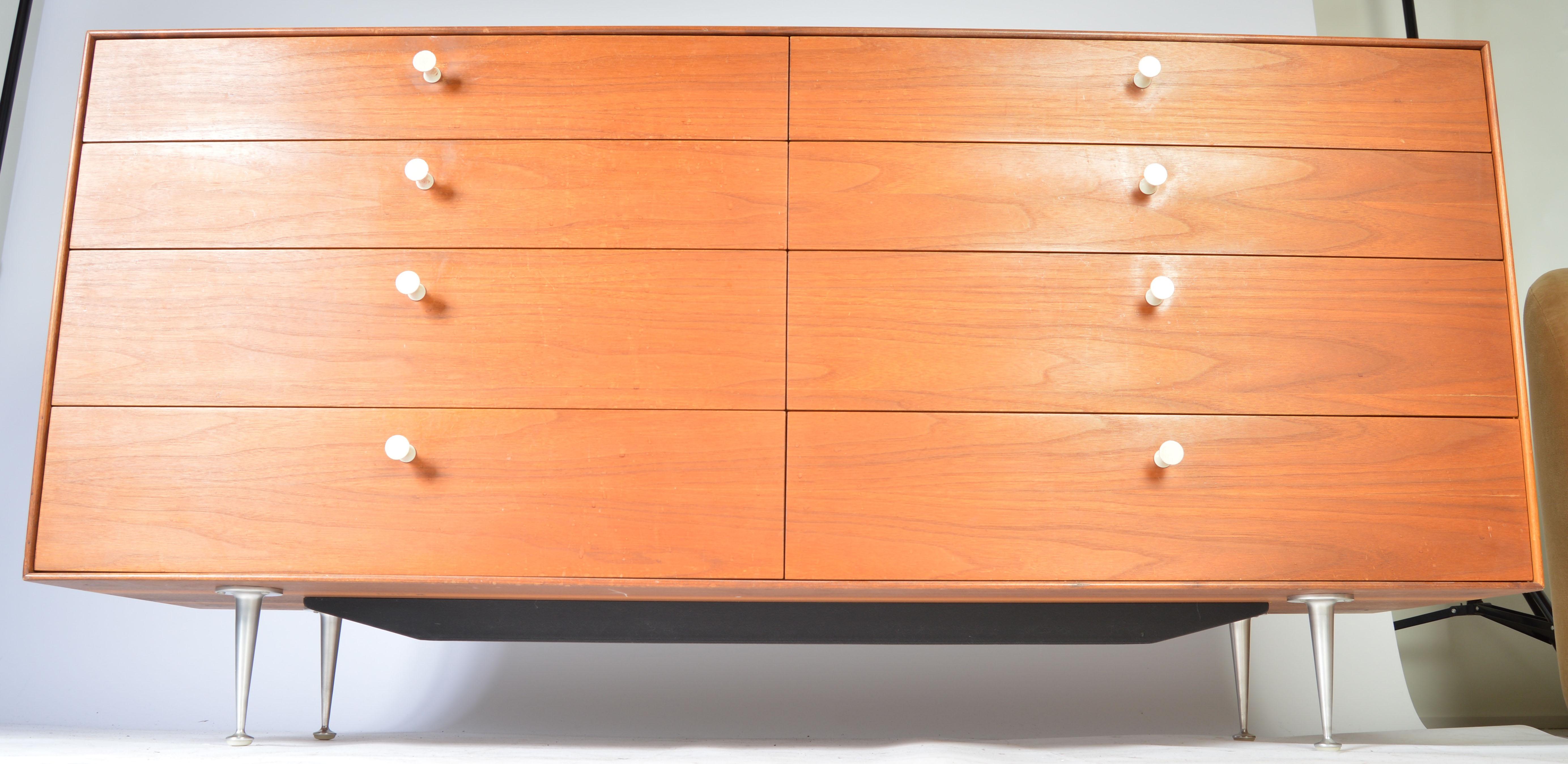 A vintage example of the sophisticated 8-drawer 'Thin Edge' dresser in teak designed by George Nelson for Herman Miller having original porcelain pulls, spun aluminum legs, black steel support bar underneath the case and high gloss white tray based