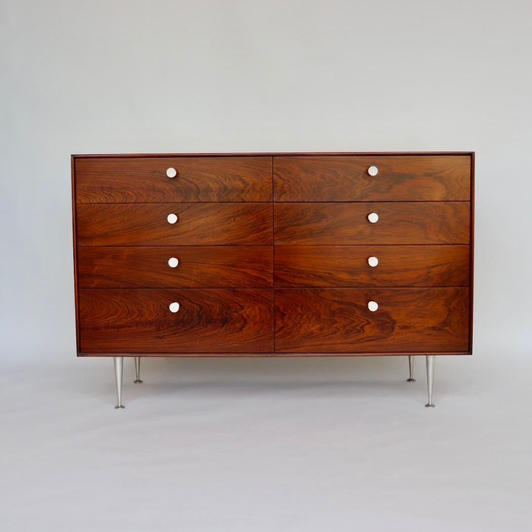 We have restored this George Nelson thin edge dresser for Herman Miller back to excellent condition. 

This thin edge is a collectors' dream, a Mid- Century Modern rosewood 8 drawers chest with original white hour glass shape porcelain knobs,