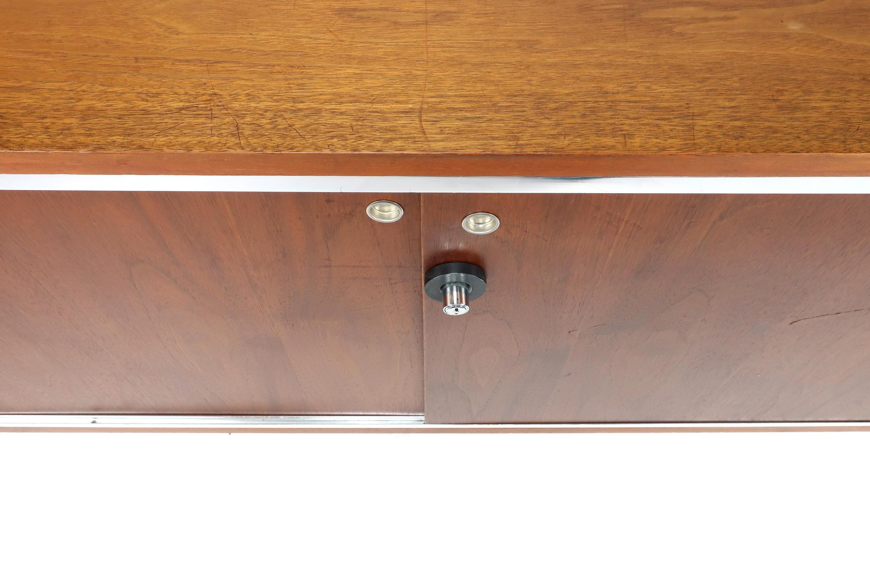 An exceptional Mid-Century Modern George Nelson Executive Office Group credenza for Herman Miller. Walnut case with rich grain and original finish, walnut top, chrome accents and legs, and two walnut veneer sliding doors with chrome pulls.