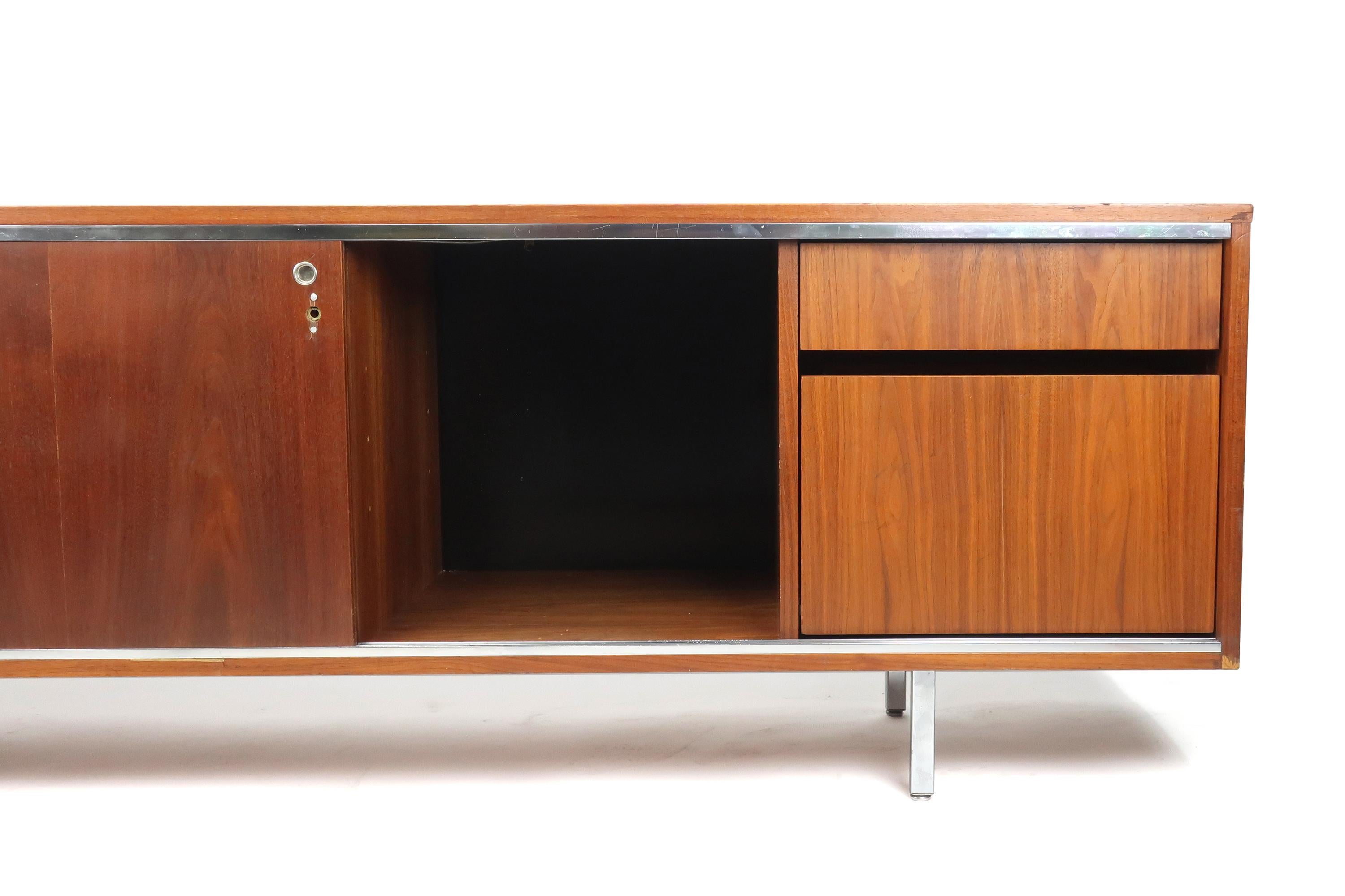 An exceptional Mid-Century Modern George Nelson executive office group credenza for Herman Miller. Walnut case with rich grain and original finish, well preserved walnut top, chrome accents and original legs, and two walnut veneer sliding doors with