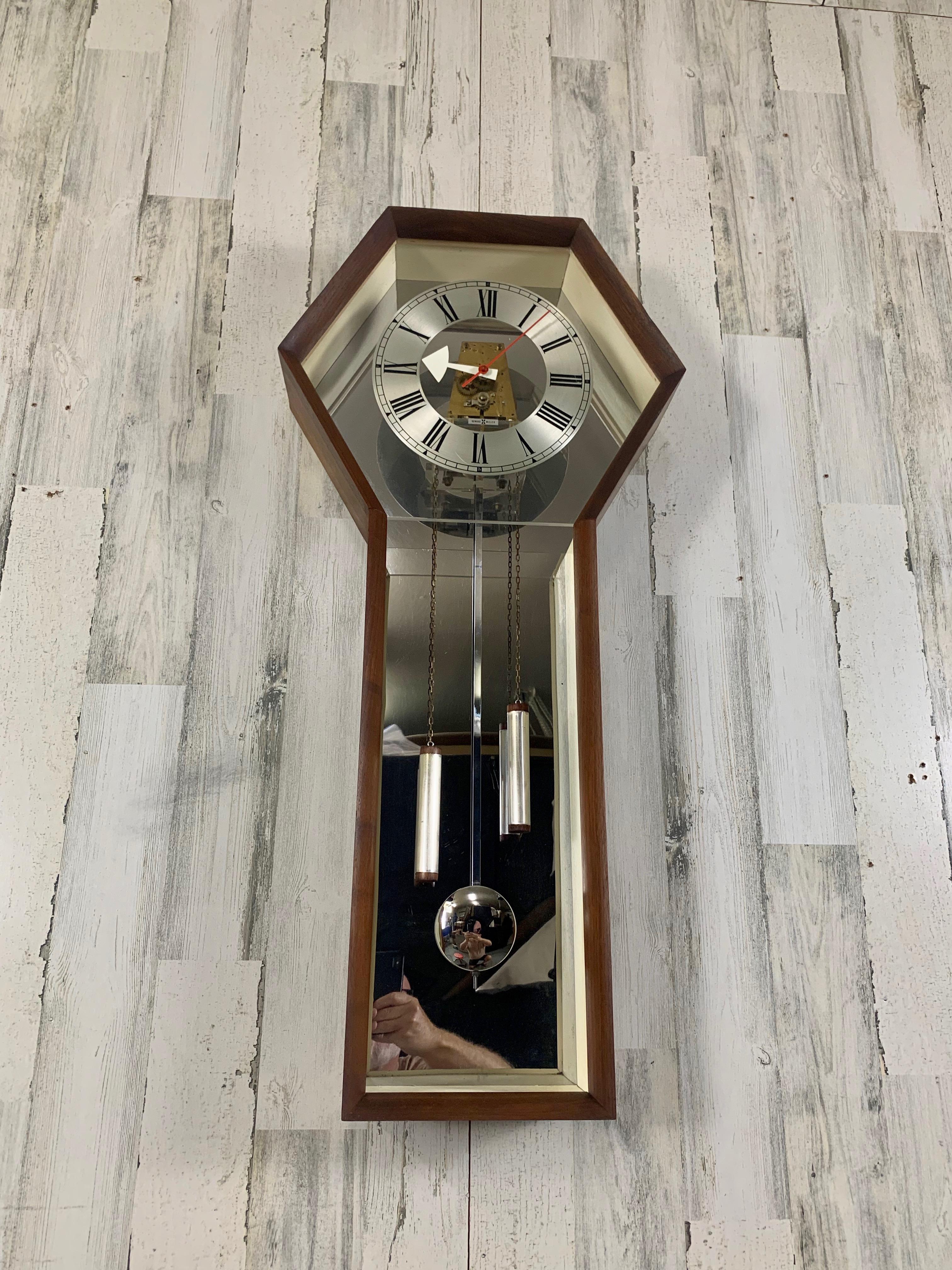 Designed by George Nelson for Howard Miller clock company. Beautiful walnut case with white and chrome interior The clock is a spring driven movement the weights are there for decoration, the movement is anchored to the Lucite face to give the