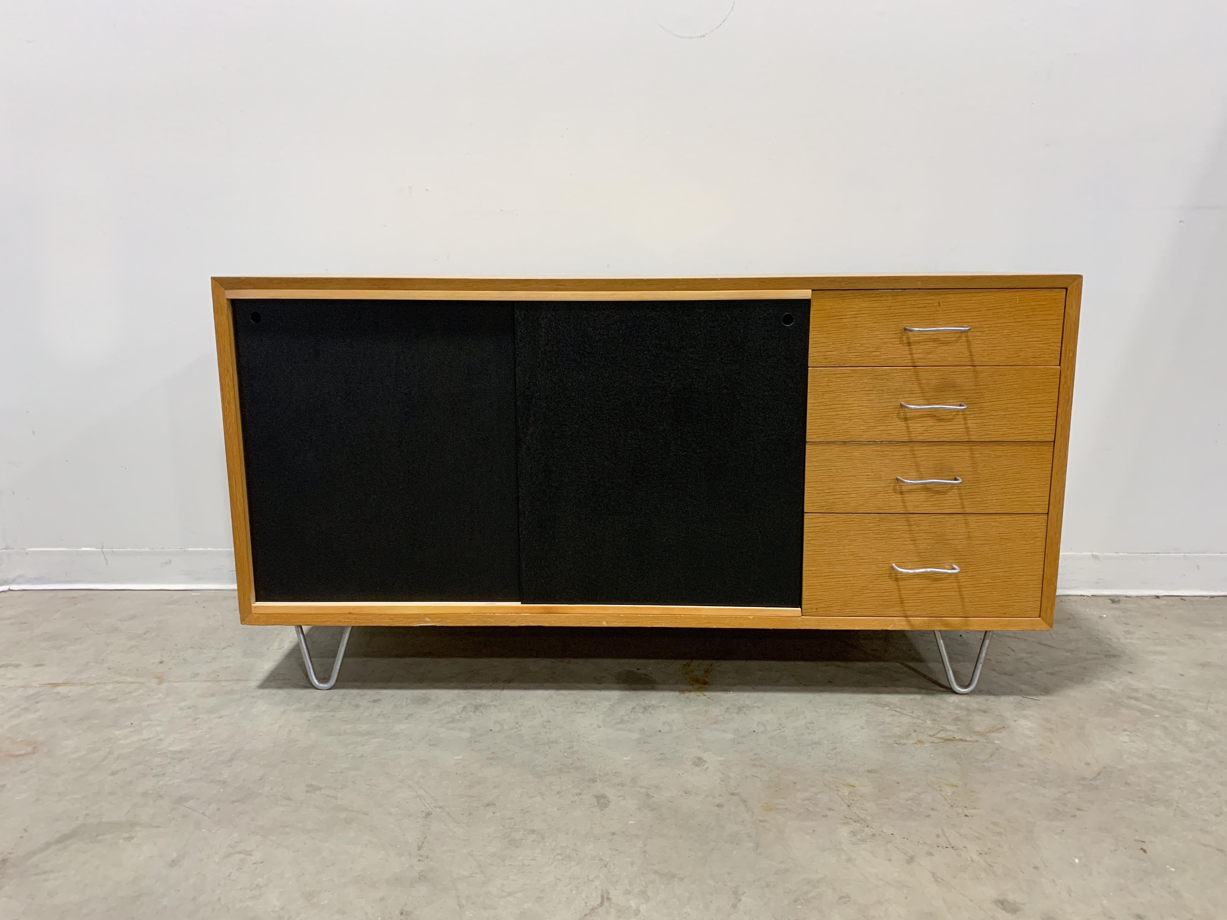Unique sideboard from Herman Miller's BCS line in the early 1950s. Blonde oak veneered cabinet with bent aluminium pulls and hairpin legs. This cabinet has been modified to include sliding doors. Originally the cabinet had normal swing doors but