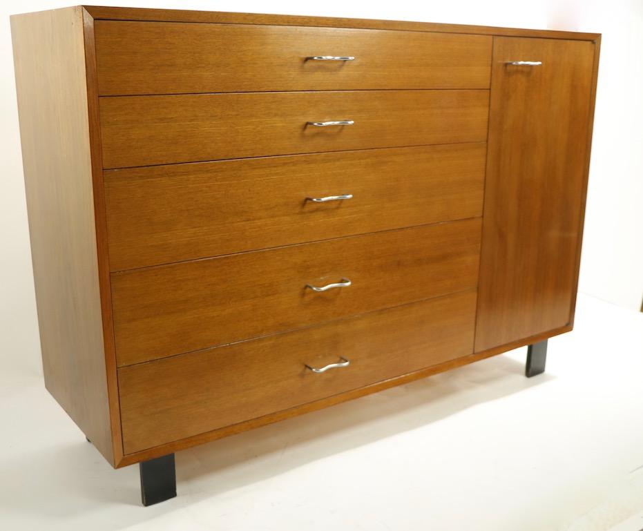 Classic midcentury cabinet from recognized master of the genre George Nelson for Herman Miller. The chest features a bank of five drawers flanked by a door, which opens to reveal shelved storage space. The piece is from the Basic Series, it is
