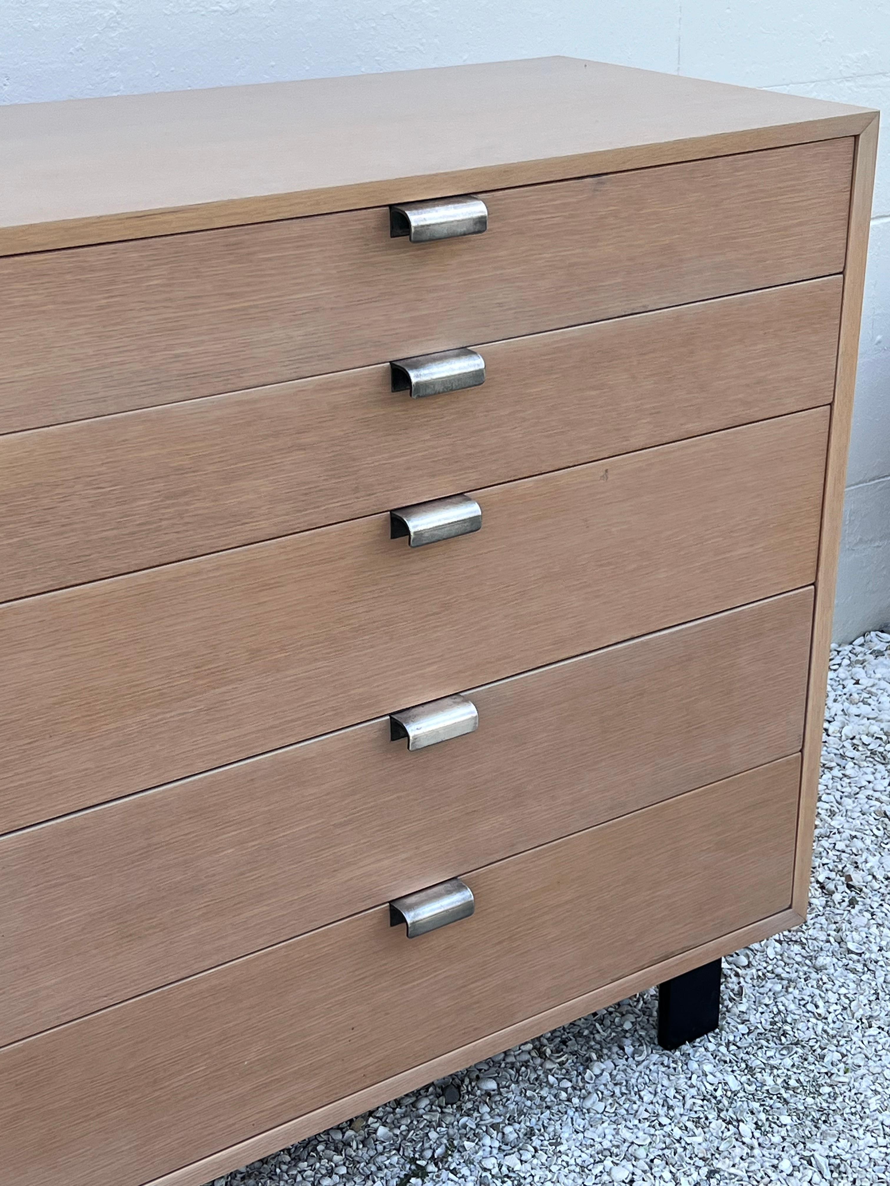 Un mueble clásico de George Nelson para Herman Miller, de la serie básica, con 5 cajones en un lado y un armario de caballero en el otro. Se trata de una versión poco común en roble. Acabado decapado recién renovado; también hay un par de mesillas