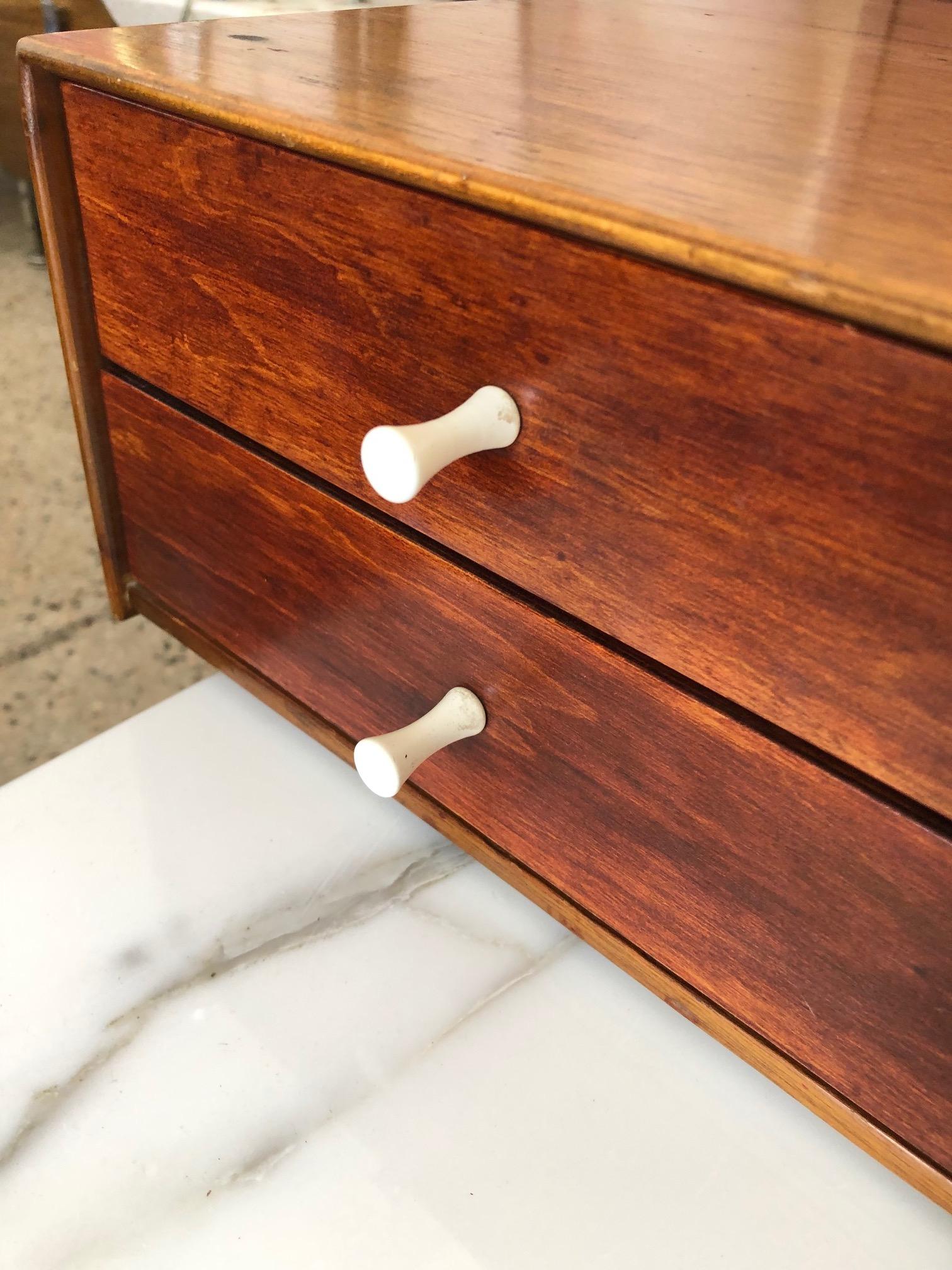 Unusual version of the George Nelson miniature/jewelry chest #5215. This one features the white formica on the bottom of the case not the top as is more typical. Teak wood construction with original porcelain knobs. Great patina that shows it age