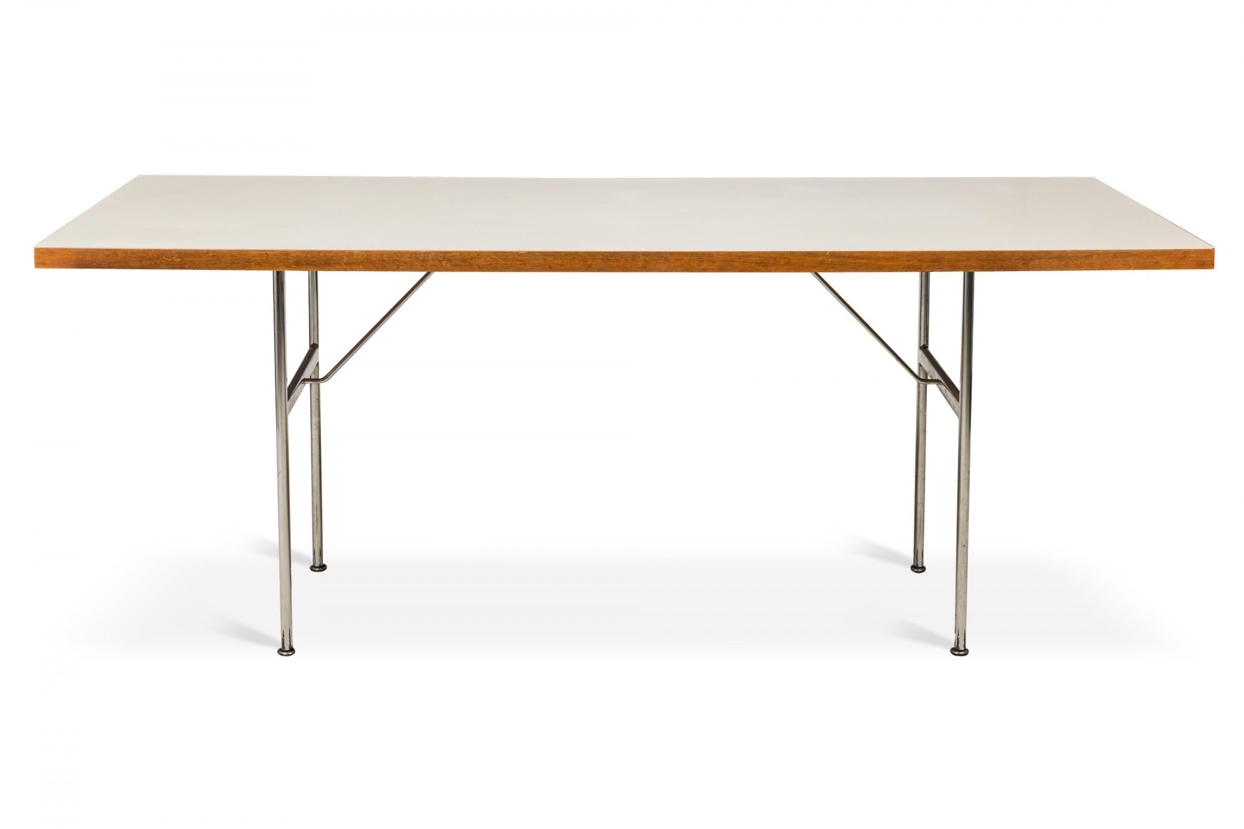 American Mid-Century dining table with a rectangular white laminate top resting on two H-shaped steel legs. (GEORGE NELSON / HERMAN MILLER).
 