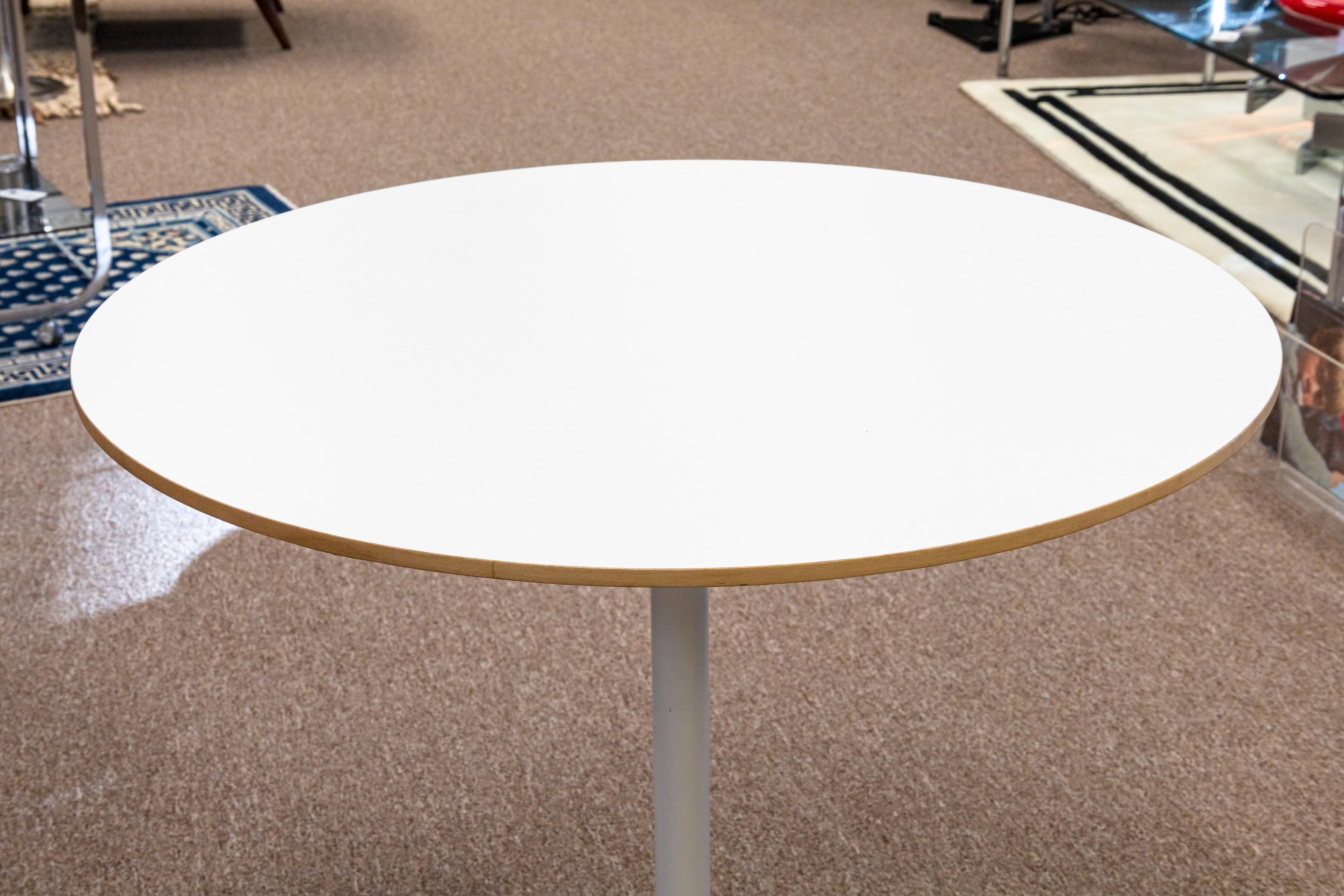 A George Nelson for Herman Miller pedestal dinette table. A fantastic little table with a white laminate table top, a wooden table, and a white aluminum base with x-shaped legs. This piece includes the original tagging on the underside as pictured