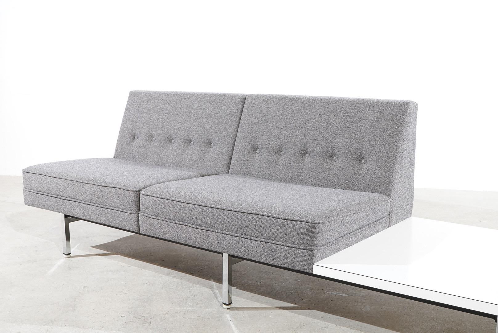 Modulares Sofa von George Nelson mit einer starken Metallstruktur und verchromten Füßen. Zwei grau gepolsterte Vintage-Sitze mit geknöpften Rückenlehnen und einer quadratischen Formica-Tischplatte. 

George Nelson (1908 - 1986). Als er in den 1930er
