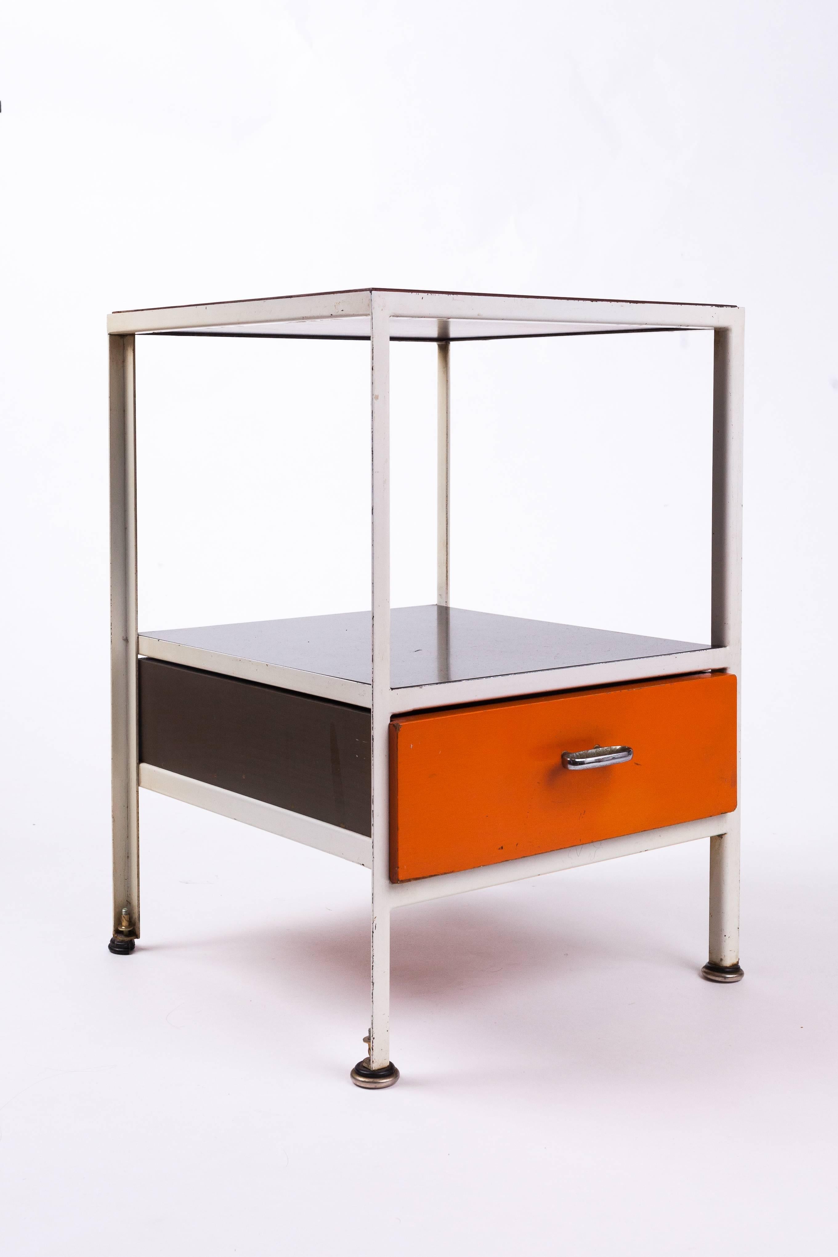 George Nelson (1908–1986)

Streamlined and playful early steel-frame nightstand or end table by George Nelson for Herman Miller, in orange, brown, and white enameled steel with a lacquered wood top and aluminum handle. The light, geometric design
