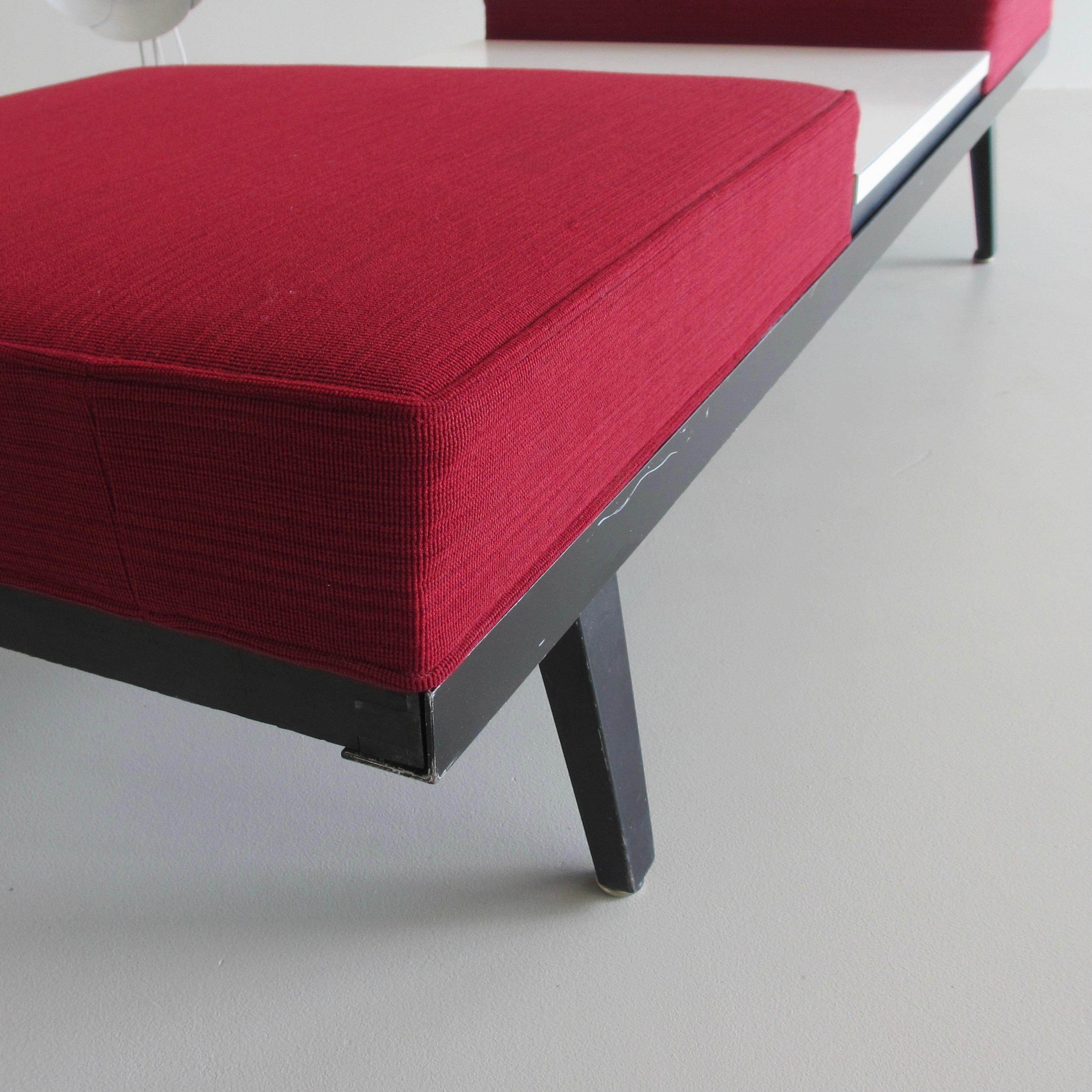 Steel frame bench and table designed by George Nelson. U.S.A., Herman Miller, 1955.

Black steel frame with three modular parts, consisting of two cushions upholstered in red wool material, plus a white Formica table mudule. These three modules