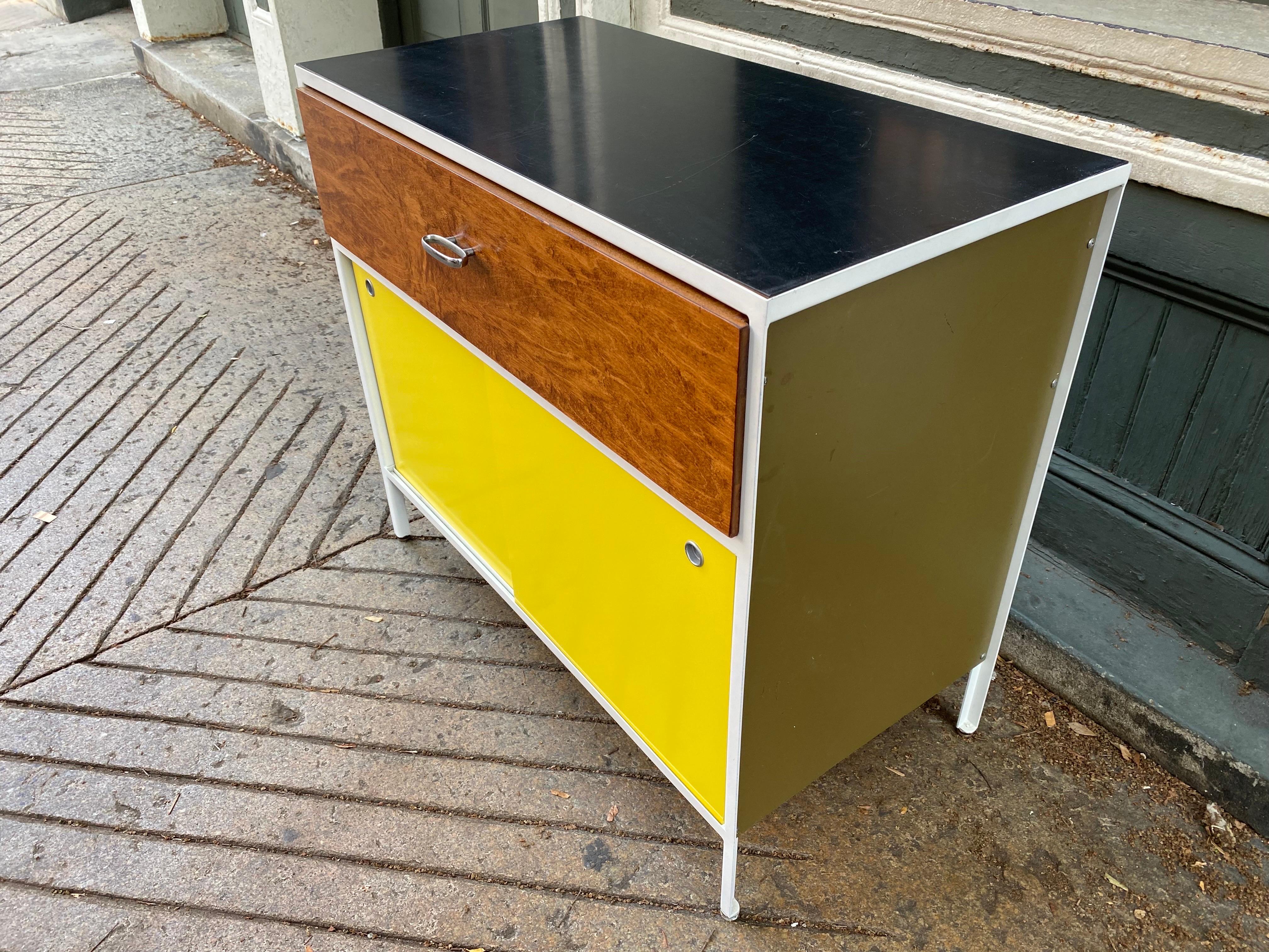George Nelson steel frame cabinet. One walnut front drawer on top and 2 Yellow Sliding doors. Steel Frame and drawer fronts all refinished. Side panels cleaned and polished. Original black formica top shows wear.