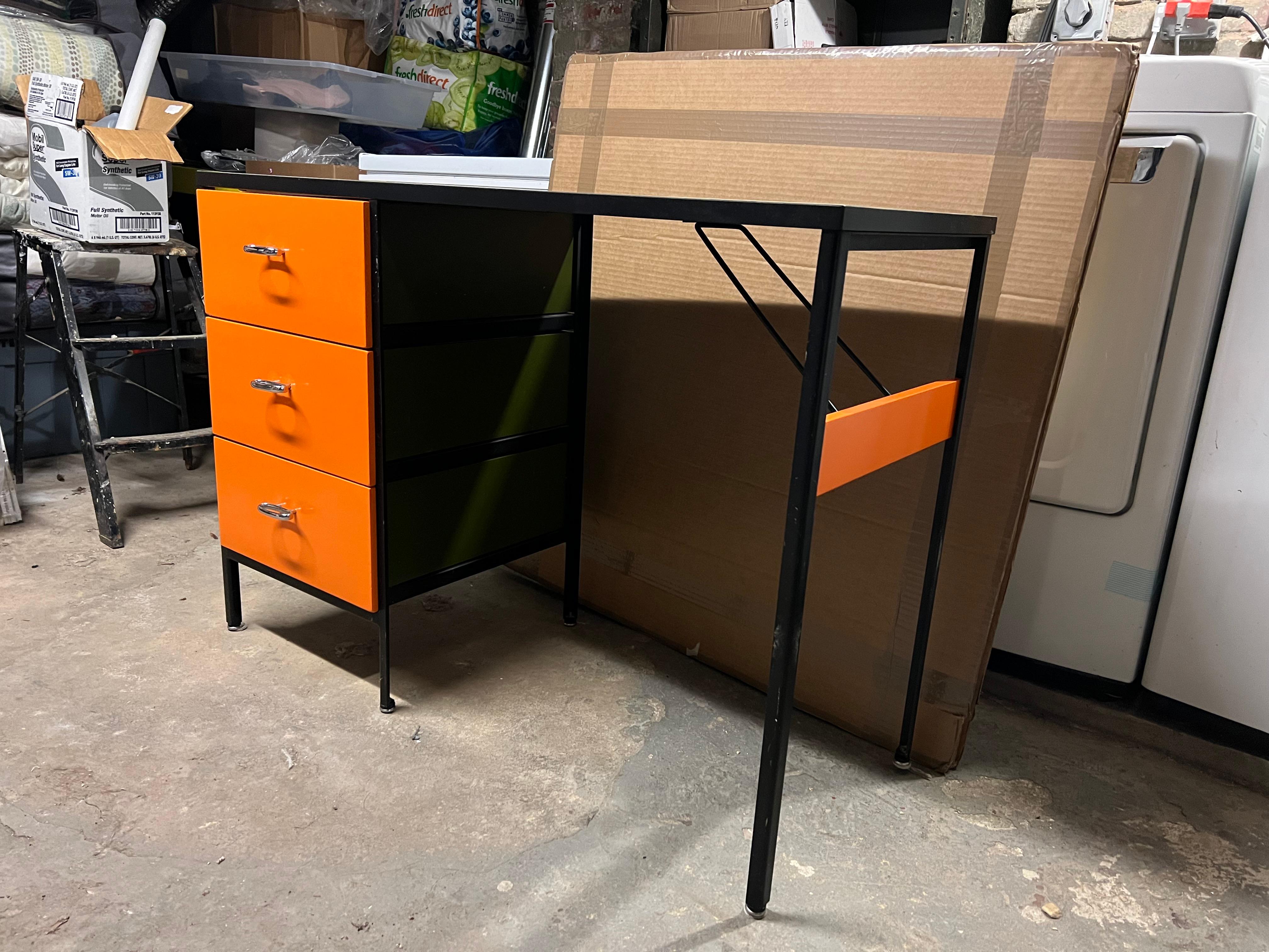 George Nelson steel frame desk, mfg. Herman Miller. Black angle steel frame with orange drawer fronts and okra colored sides. White laminate top and chrome drawer pulls. Unmarked.