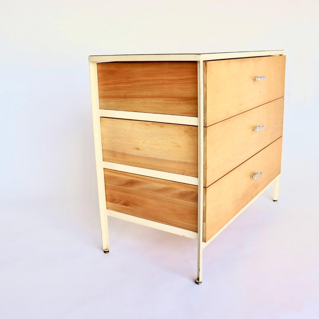 This is a rare Mid-Century Modern dresser / chest of drawers designed by George Nelson for Herman Miller. This a particularly early example, dating back to the 1950s. It has three exposed wood drawers suspended in a white steel frame. This unusual