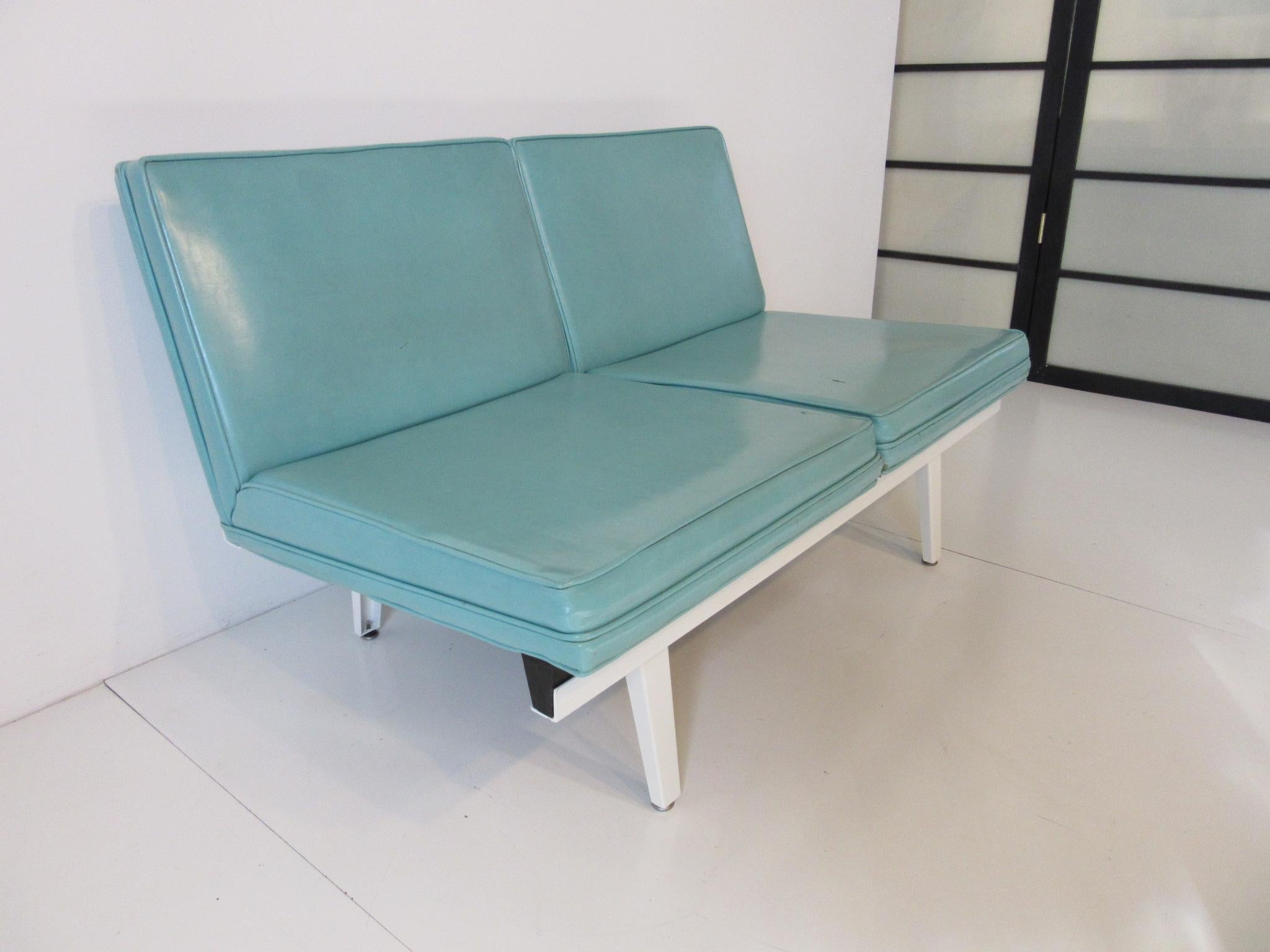 A Nelson designed steel framed love seat - sofa lounge unit with white metal frame , Rubber and metal foot pads and two turquoise Naugahyde seats . A classic design that is still fresh from the early 1950's manufactured by the Herman Miller