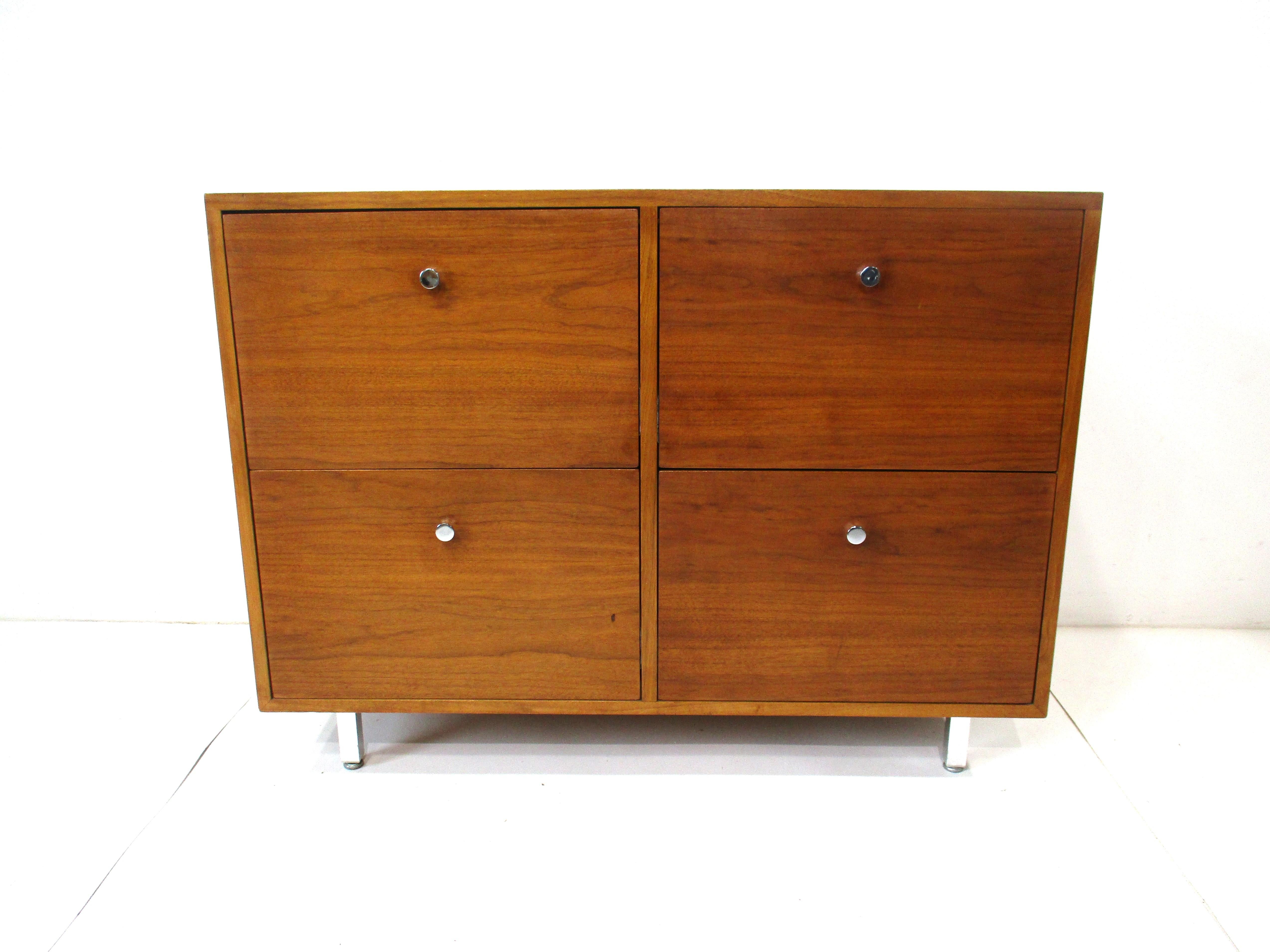 A smaller sized walnut credenza / file cabinet with four deep pull out drawers and chromed pulls . Sitting on brushed stainless steel legs with foot pads , a great piece that is in a smaller scale that can be used for a entertainment  , file cabinet