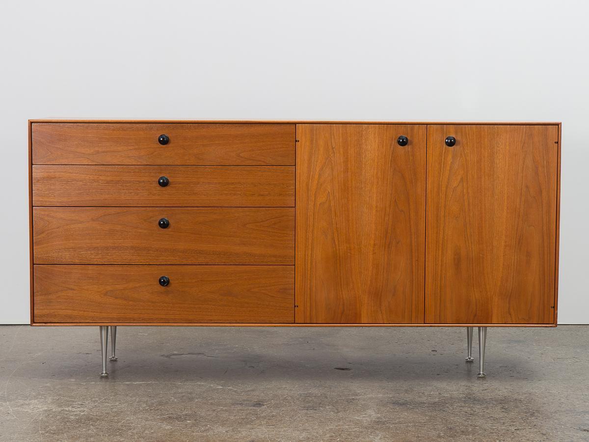 Thin edge buffet cabinet in walnut, designed by George Nelson for Herman Miller. Named for its clean lines, minimal form showcases gorgeous honey-hued walnut wood selection. Cabinet floats on aluminum champagne flute legs, finished with contrasting