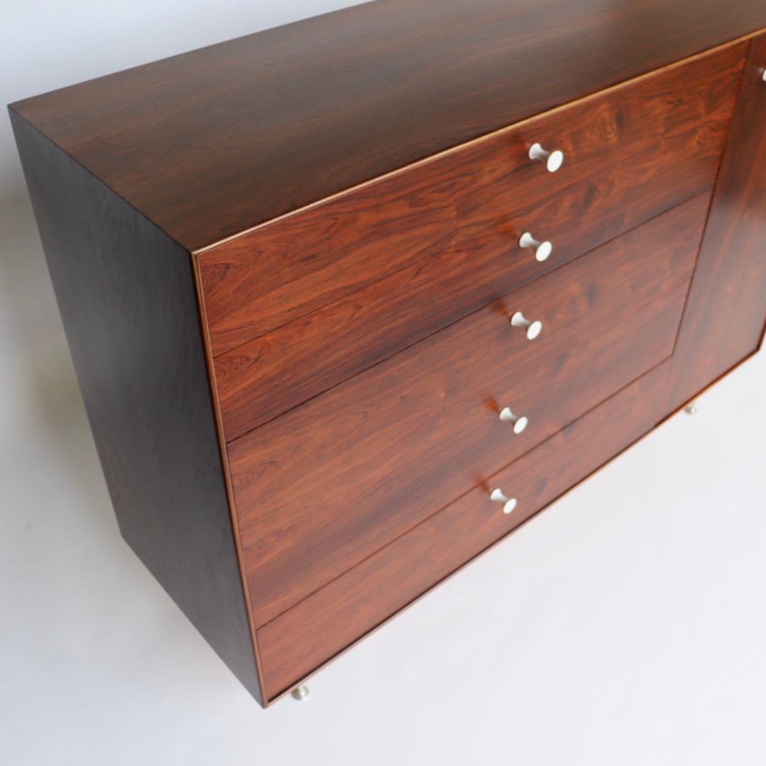 We are so excited to offer this fully-restored George Nelson 'Thin Edge' chest of drawers, model no. 5245. Executed in rosewood, it has the iconic aluminum legs and porcelain hourglass-shaped pulls. It has with single cabinet door to right and five