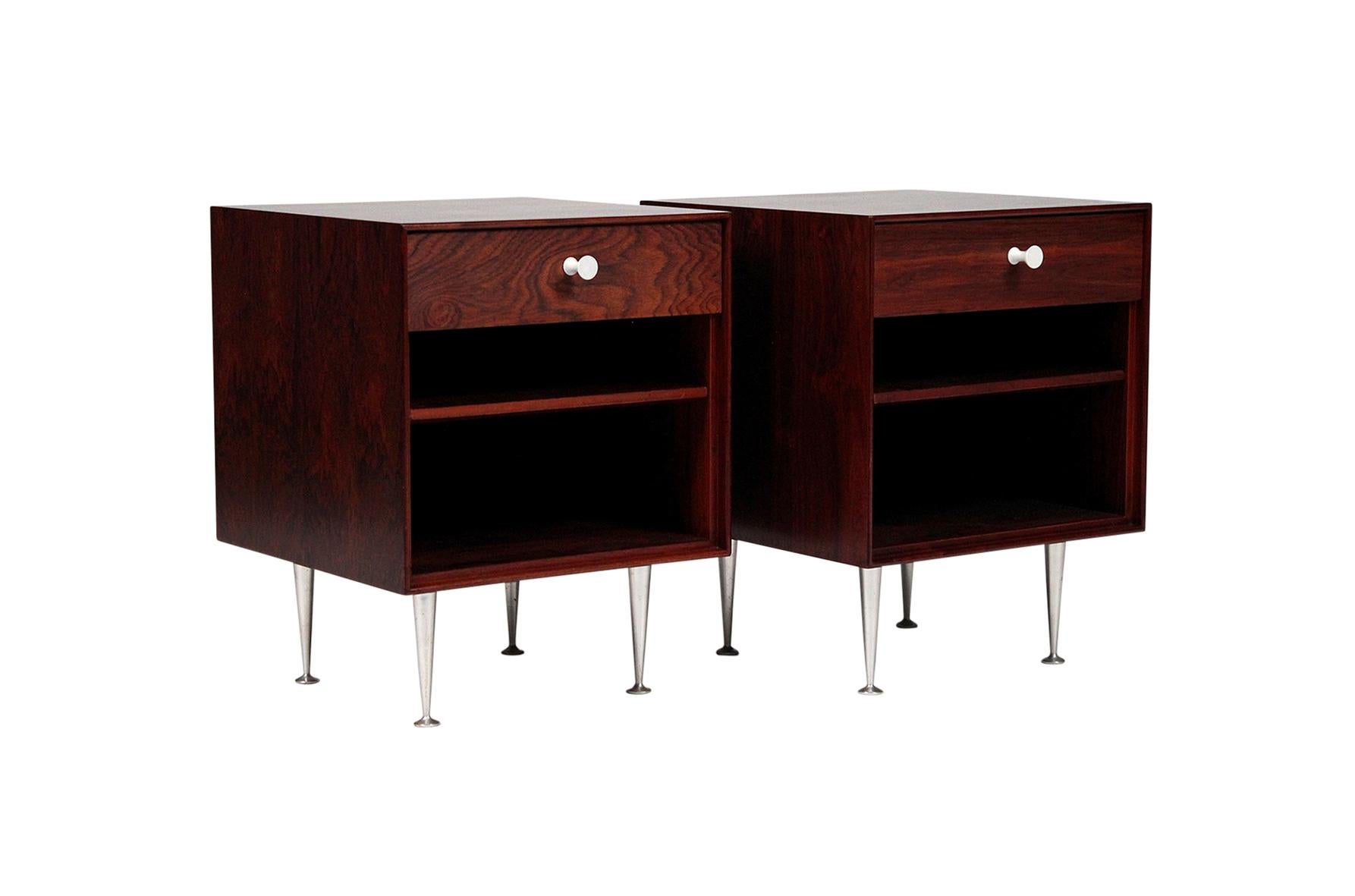Pair of George Nelson for Herman Miller thin edge nightstands. Book matched rosewood veneers with porcelain pulls and tapered aluminum legs. Rare examples of the iconic series. White metal Herman Miller label in drawer interior.