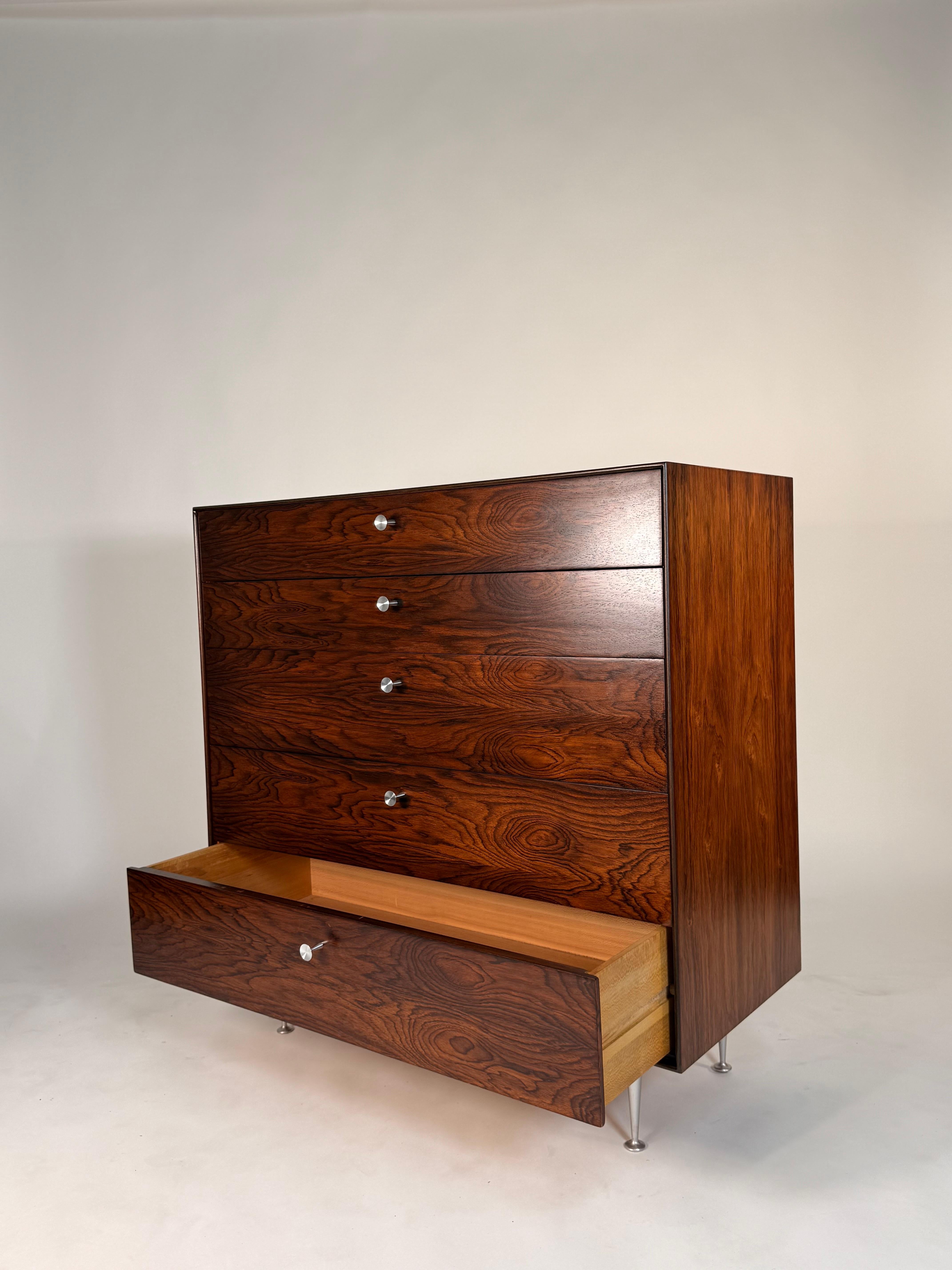 Esta cómoda alta George Nelson de bordes finos, una pieza rara y muy buscada del diseño estadounidense, ejemplifica lo mejor de la artesanía moderna de mediados de siglo. Diseñada por George Nelson para Herman Miller, esta cómoda alta presenta un