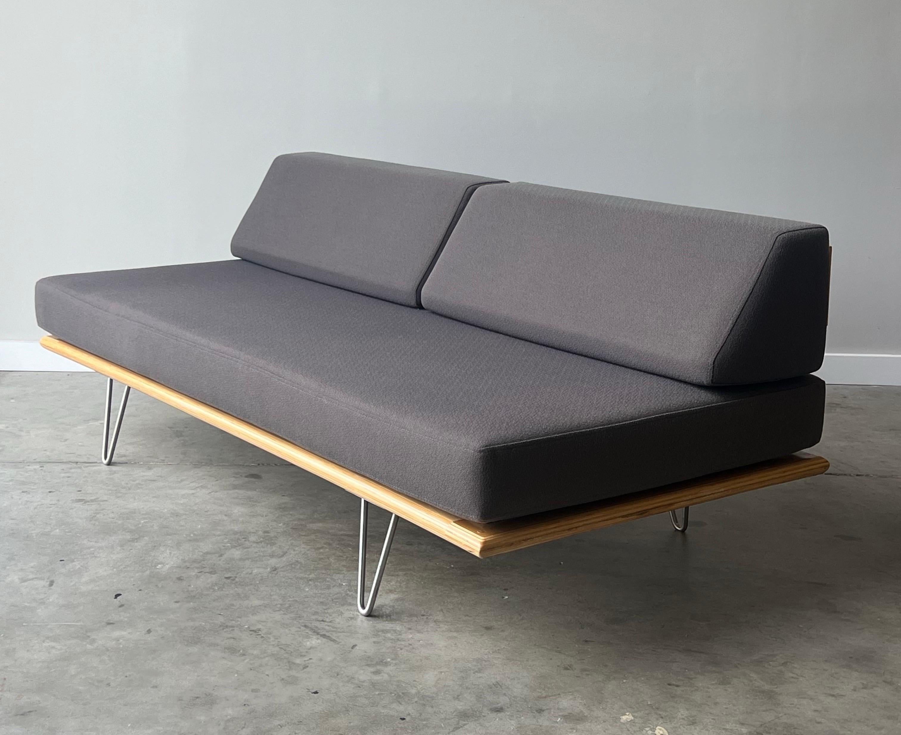 Wonderful daybed sofa manufactured by Modernica in the design of George Nelson. The frame is made from layered birch wood sitting atop steel V-legs. The backrest also features birch wood and bent steel supports. The cushions are a high-density foam
