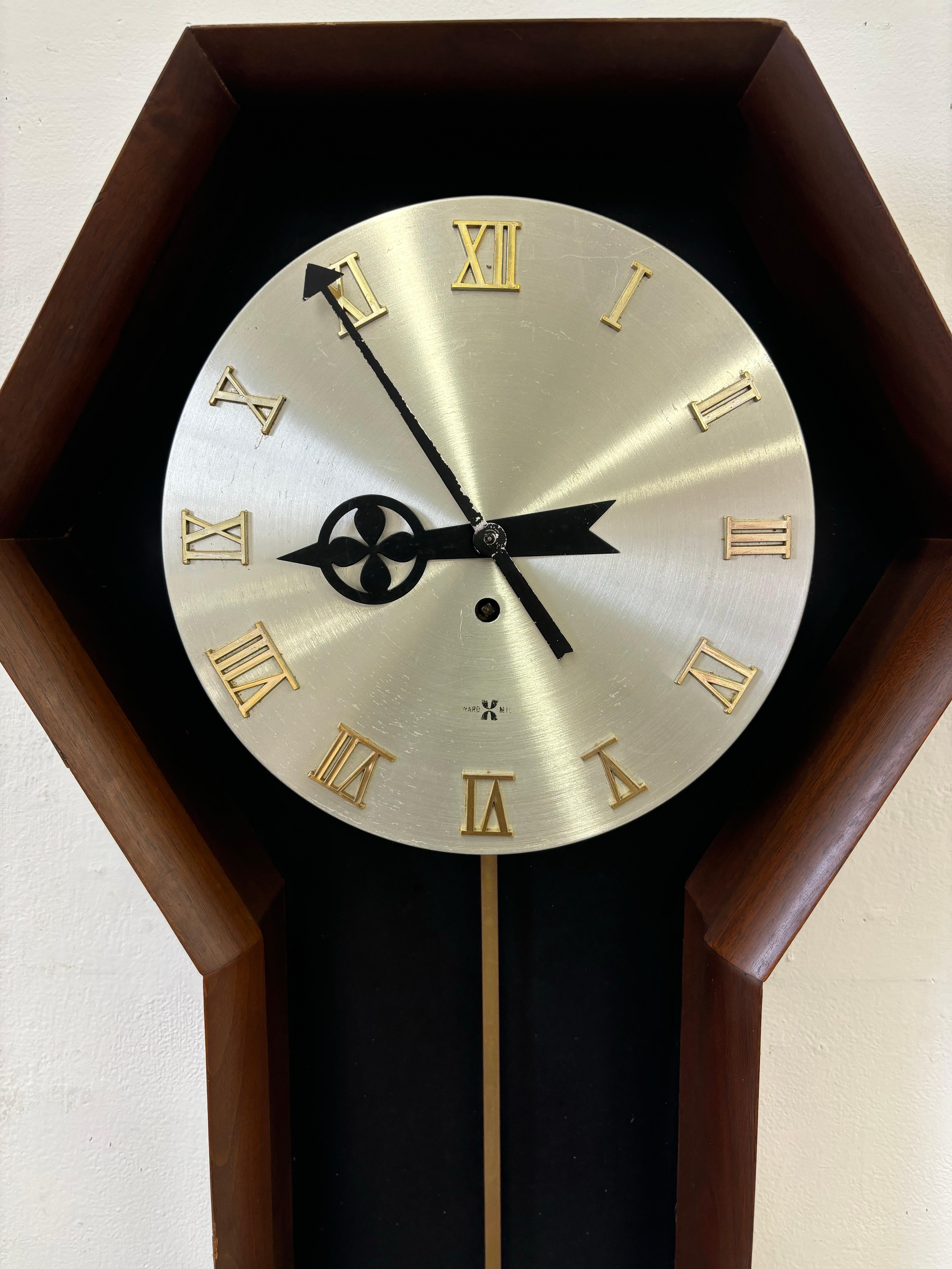 George Nelson for Howard Miller Clock Company.  Walnut outer frame with a round aluminum face.  8 day movement.  Shows signs of use and wear but overall presents well.  Original Key.
