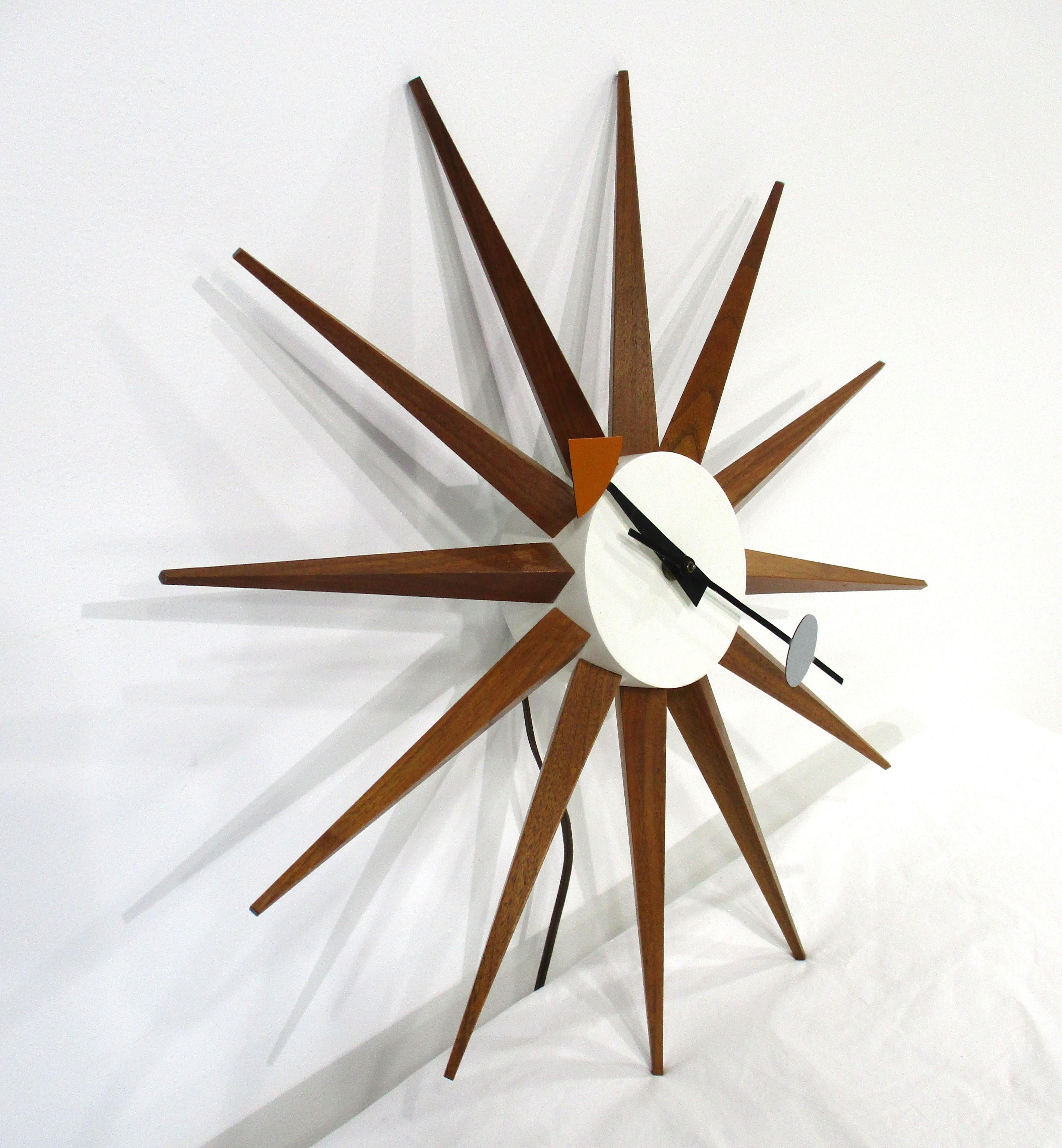 An Nelson walnut and painted white metal body spike clock with color coded minute and hour hands. An early electric model in great working condition , retains the original label and stamped numbers to the verso manufactured by the Howard Miller