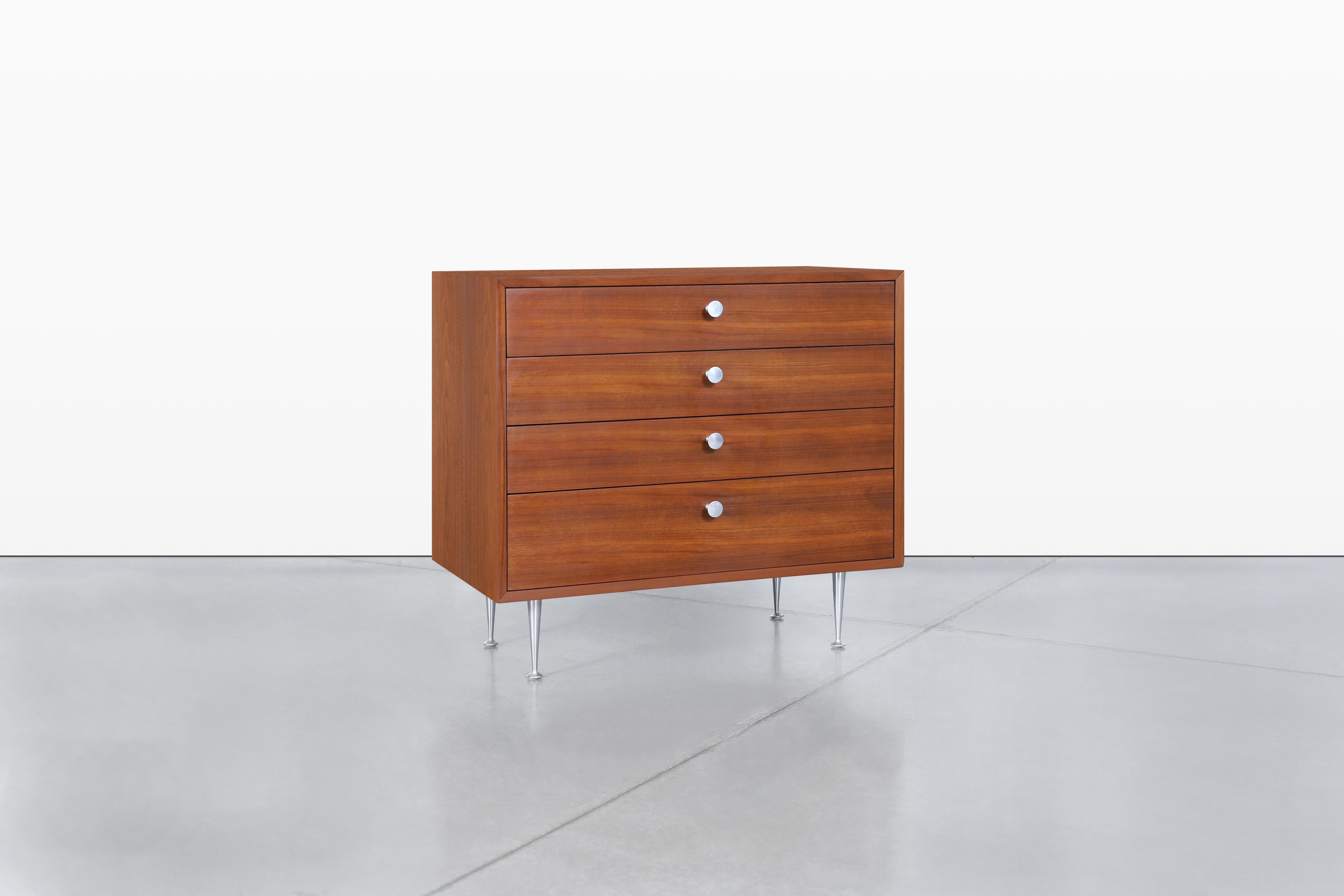 Me complace presentarte esta impresionante cómoda de nogal de mediados de siglo, diseñada por el célebre George Nelson para Herman Miller en la década de 1950. Esta pieza no es sólo un mueble; es una declaración de excelencia en el diseño y de