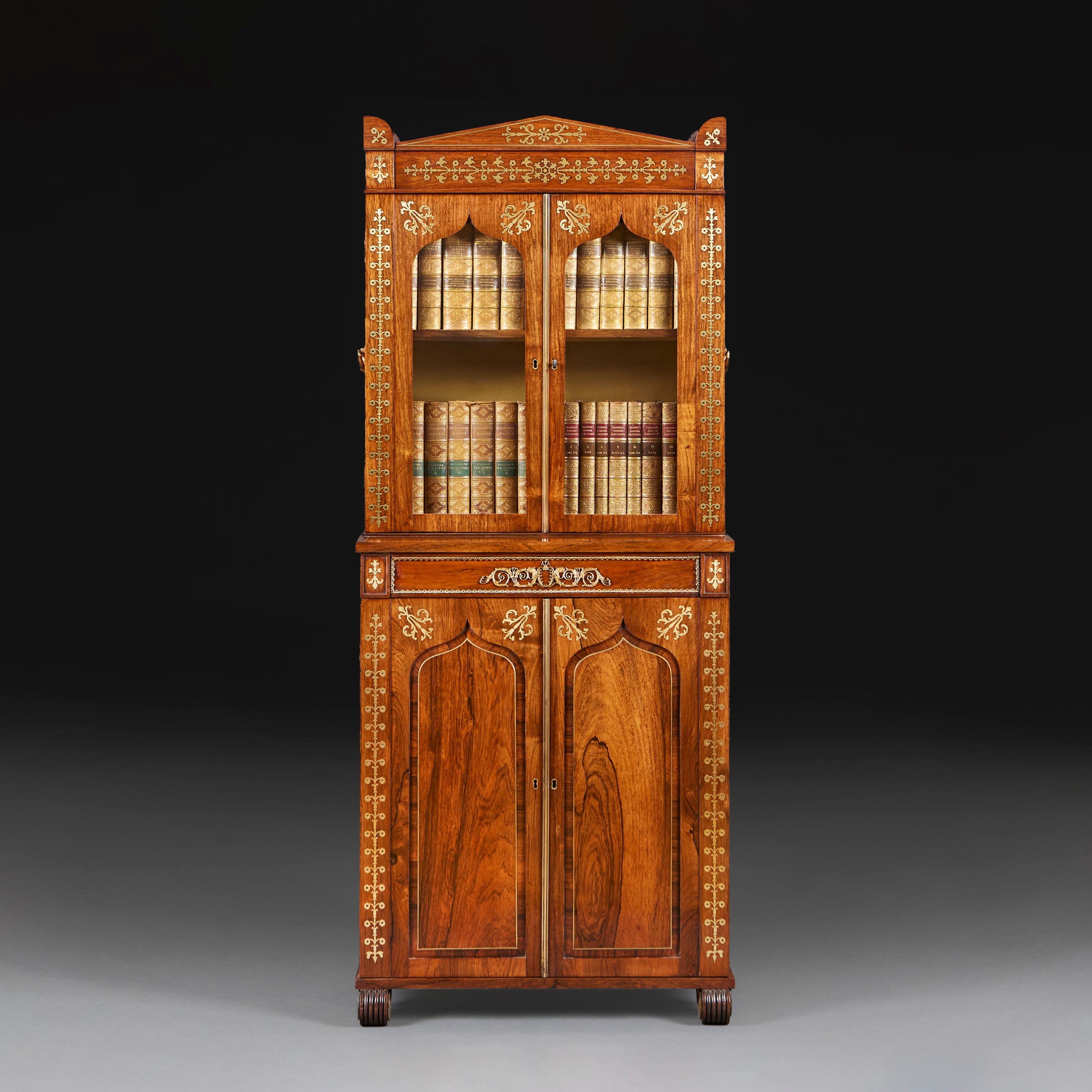 A fine early nineteenth century goncalo alves cabinet with intricate brass inlay of foliate designs, the top half with glazed cabinet doors opening to reveal a silk lined interior, surmounted with architectural crenelated pediment, the lower half
