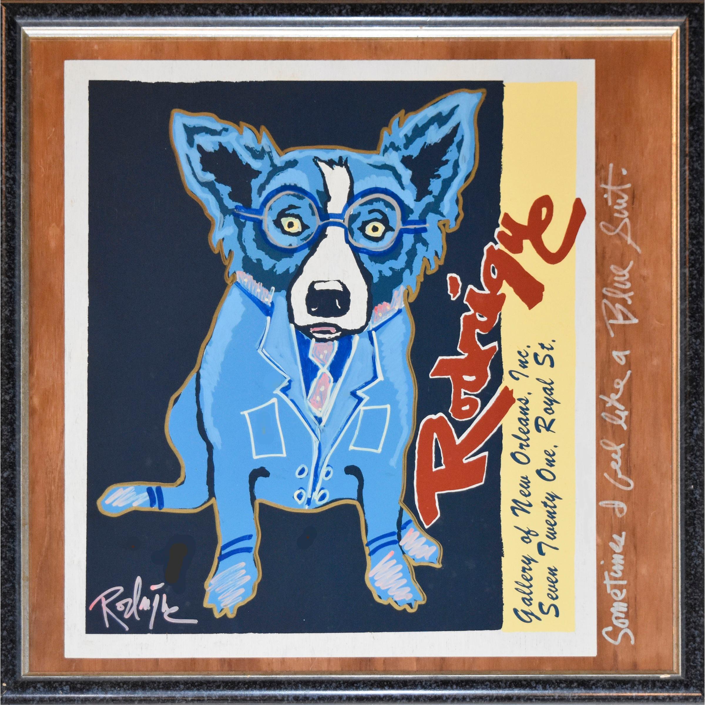 This Blue Dog work consists of a Blue Dog in a Blue Suit sitting on a black background.  There is a side strip of yellow with “Rodrigue” written in red and an address for the gallery.  The painting is attached to a piece of plywood with the words