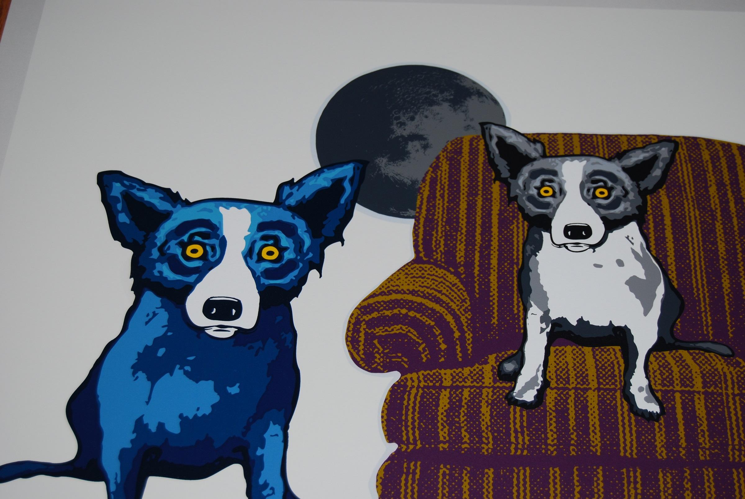 This Blue Dog work consists of a white background, 3 dogs, 1 each black & white, Red and blue.  The black & white dog is sitting on a 2-toned brown overstuffed chair while the blue & red dogs are sitting on either side of the chair.  There is a