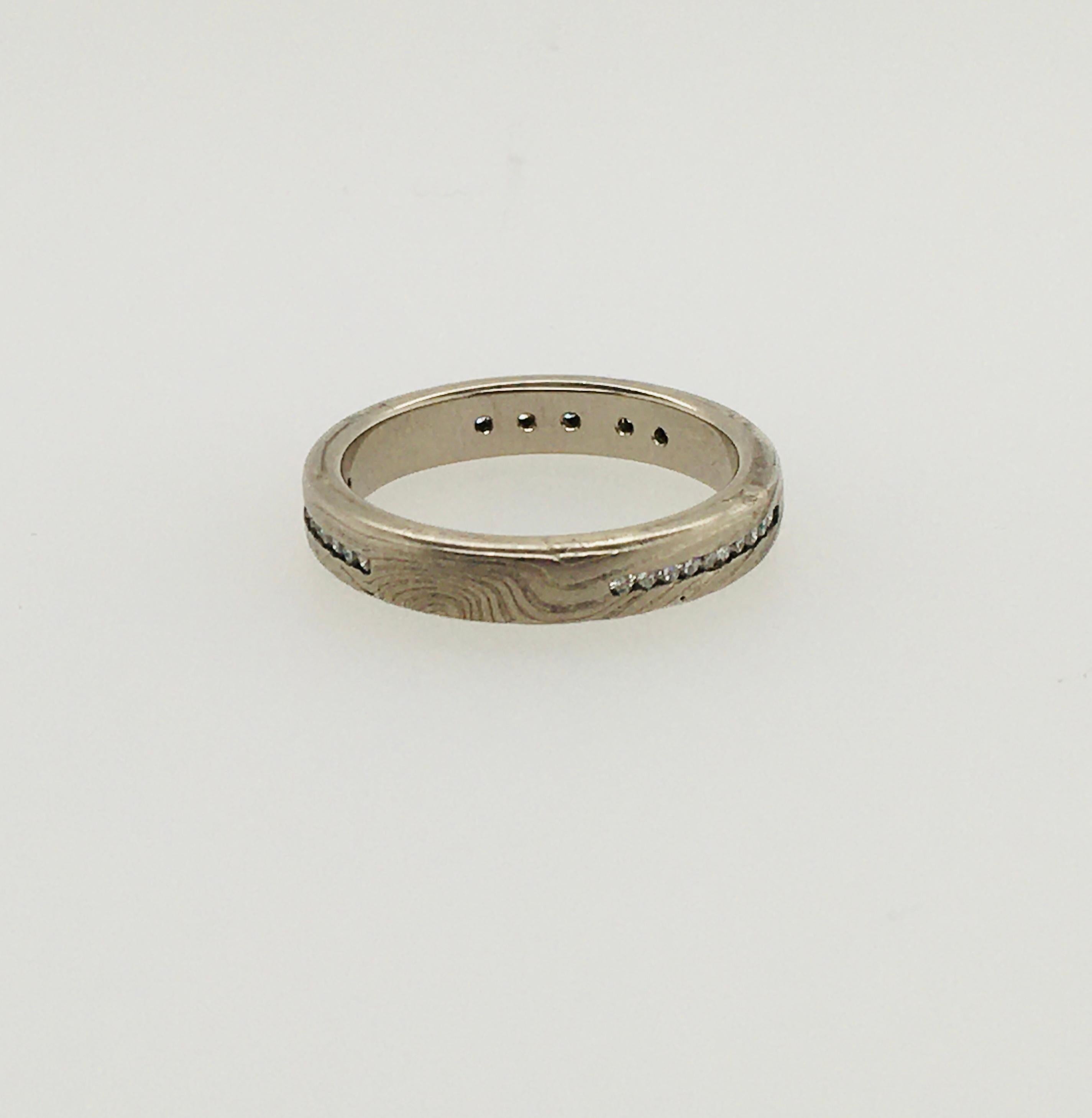 A striking George Sawyer 3.6 mm 14K gray gold and etched sterling silver flat band in the distinctive Mokume style. The ring features 3 channels of 10 round diamonds, each set in 14KW gold, .14 TCW.   Interior stamp reads 